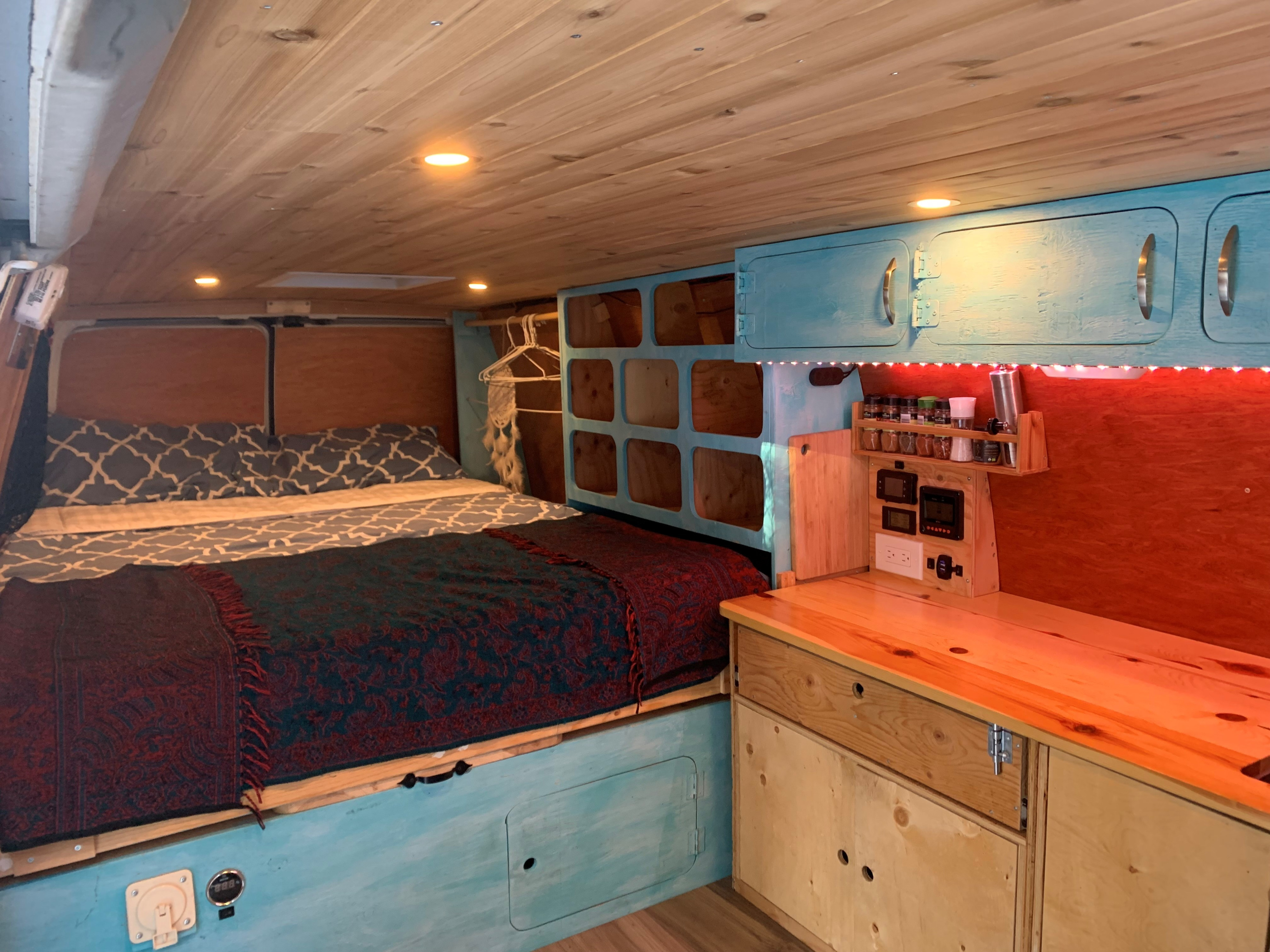Cozy RV rental interior with a bed, wood ceiling, blue cabinets, and kitchenette. Perfect for road trips and camping.. Ford Econolline 250s 2007