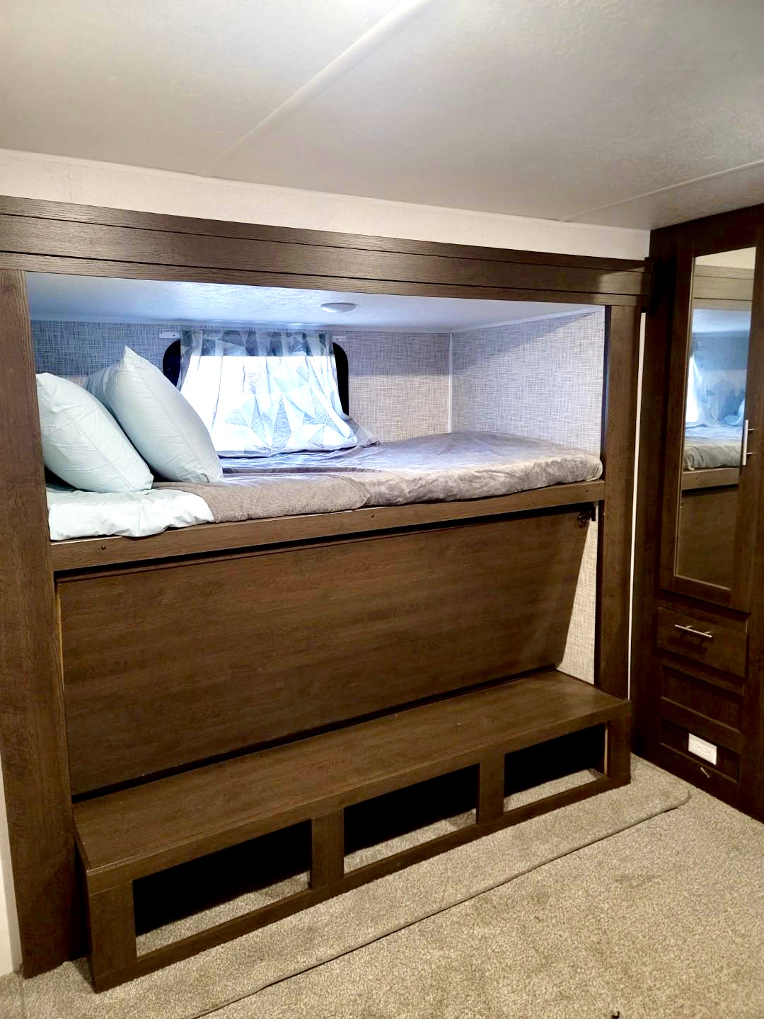 This RV rental bunk bed setup offers cozy sleeping & a lower bench. Ideal for family camping trips and comfortable travel.. Forest River Wildwood 2019