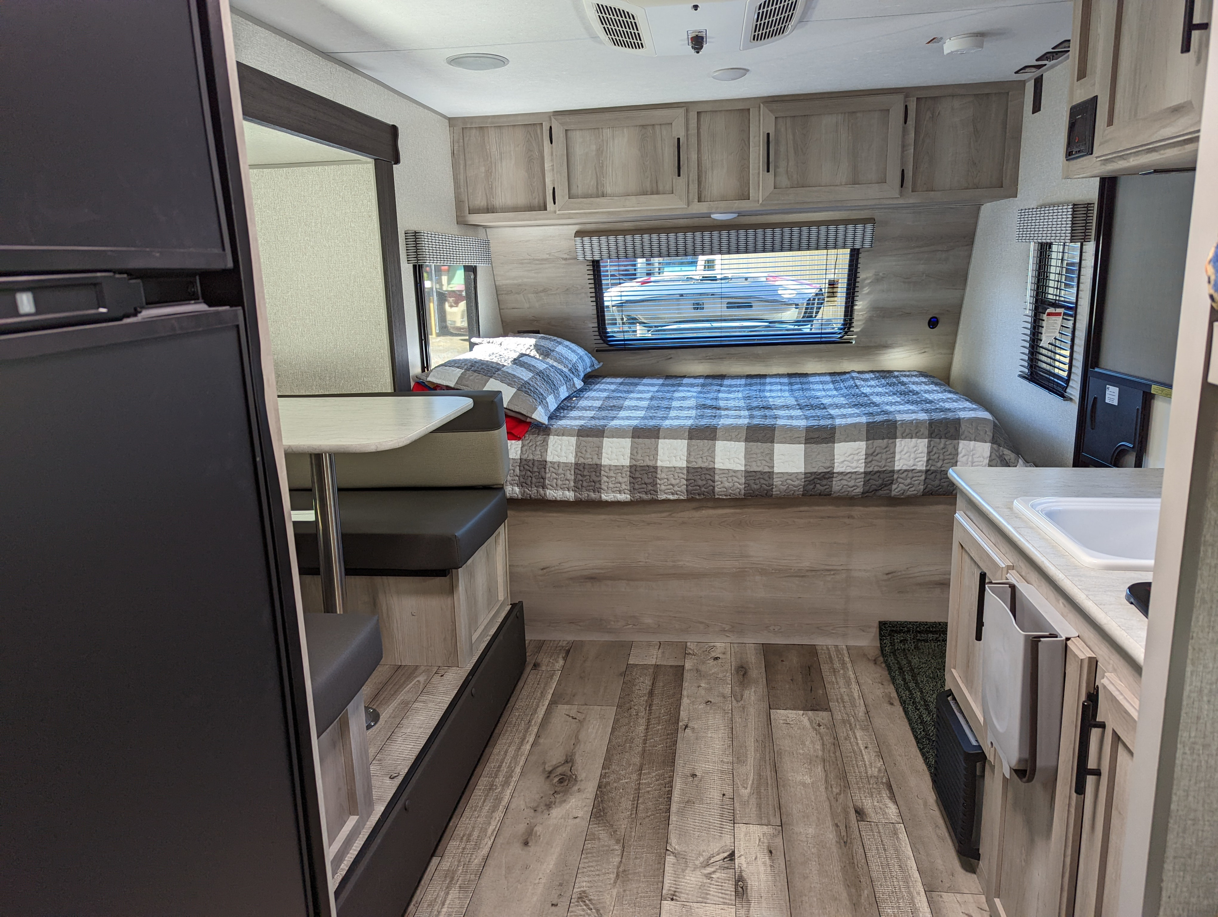 Cozy RV rental interior with a bed, dinette, and kitchenette, showcasing a modern compact layout for travel.. KZ 191BHK 2022