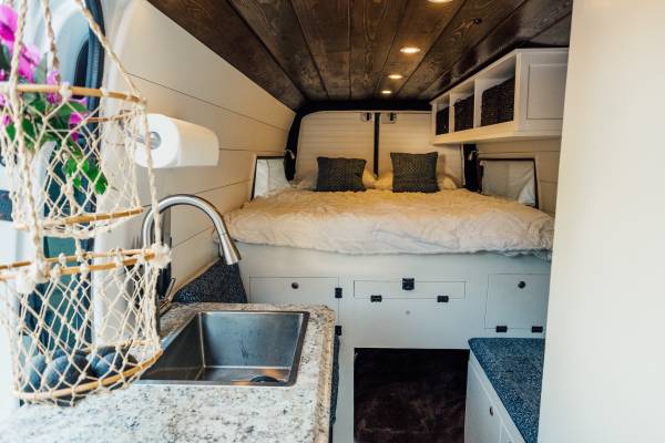Modern RV rental features a cozy bed, fully equipped kitchen with sink, and smart storage solutions for travel.. Mercedes-Benz Sprinter 2013
