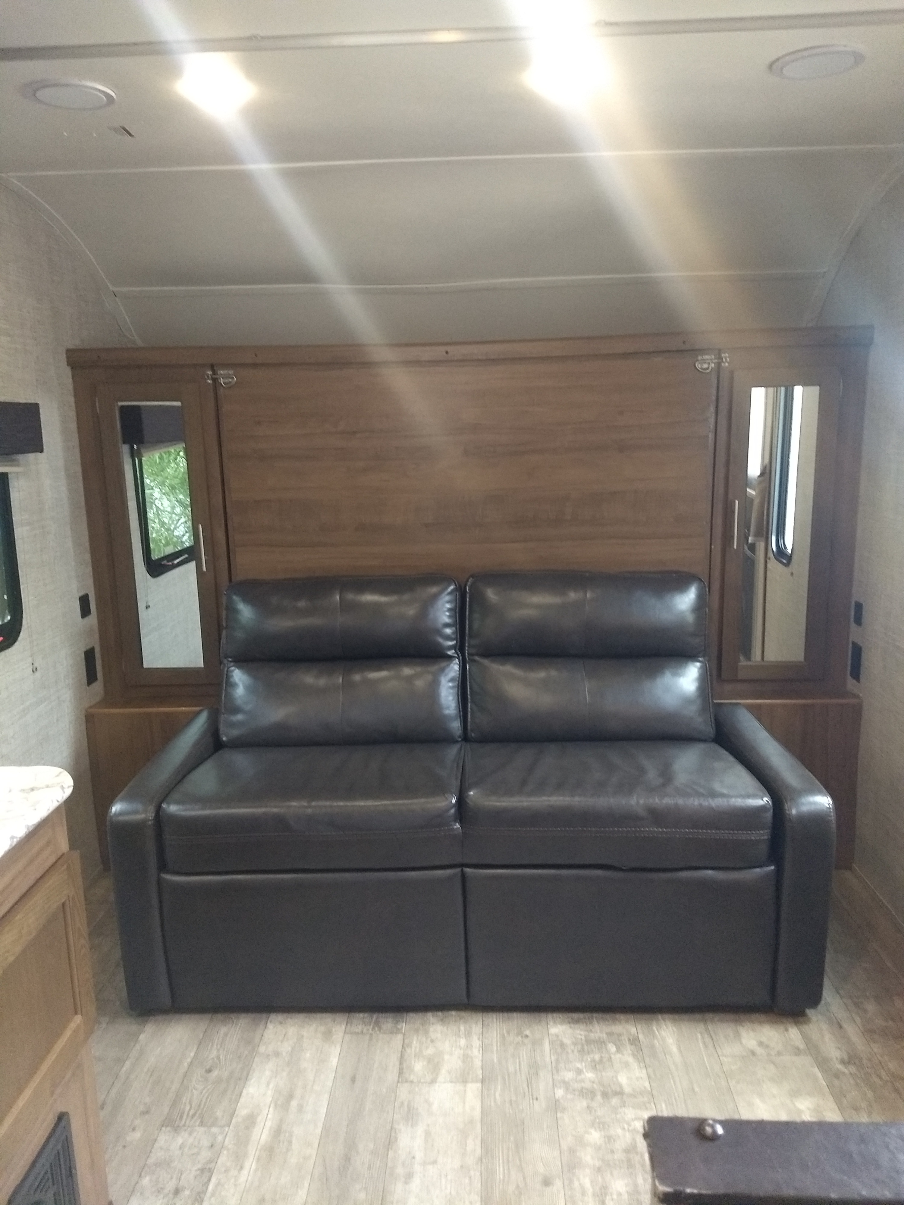 RV rental: Cozy interior with a dark sofa, wood-paneled wall with mirrors, and light flooring.. Gulf Stream Amerilite 2020