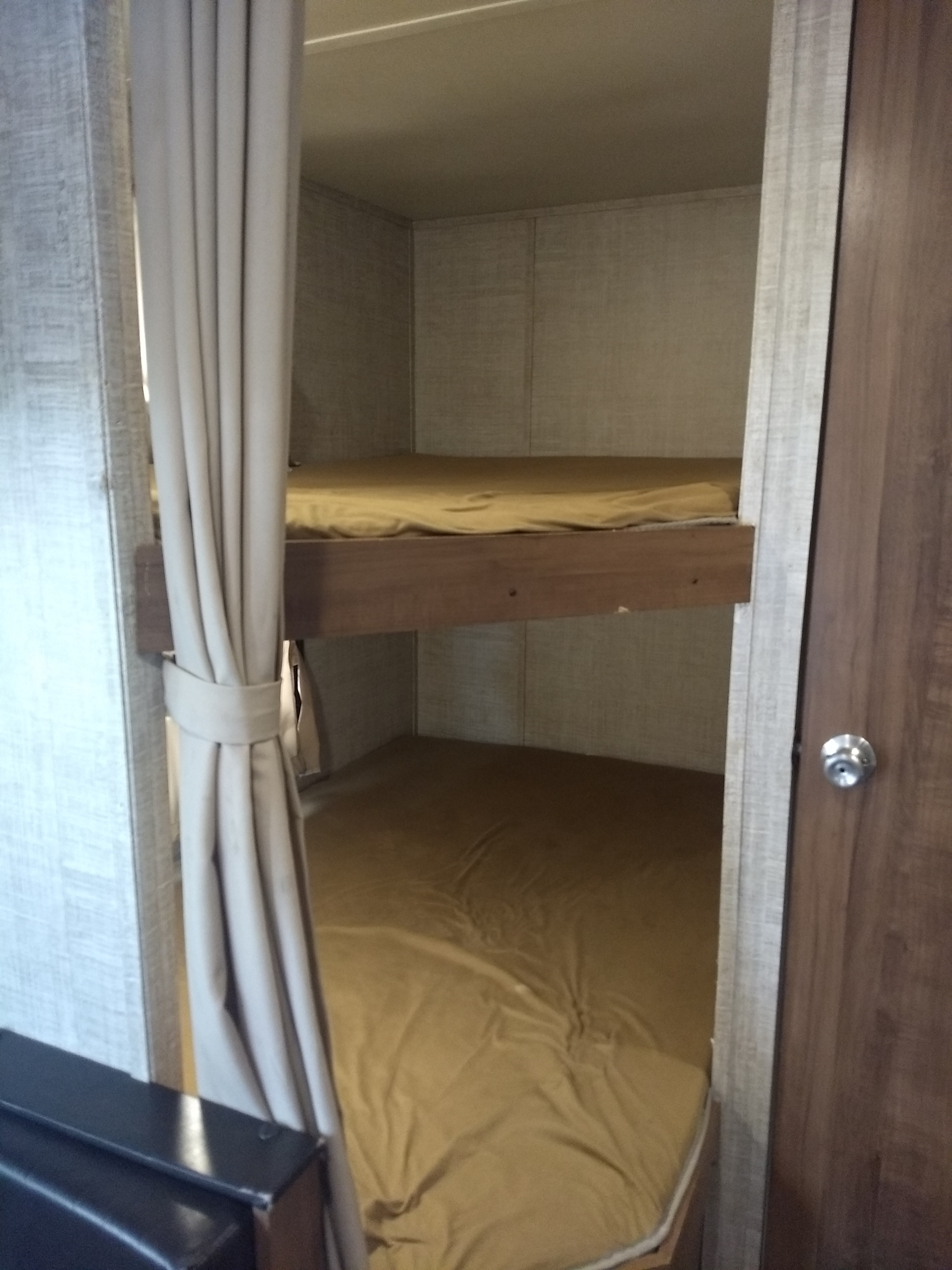 RV rental: two bunk beds with mustard sheets, visible through a partially open privacy curtain, offering cozy space.. Gulf Stream Amerilite 2020