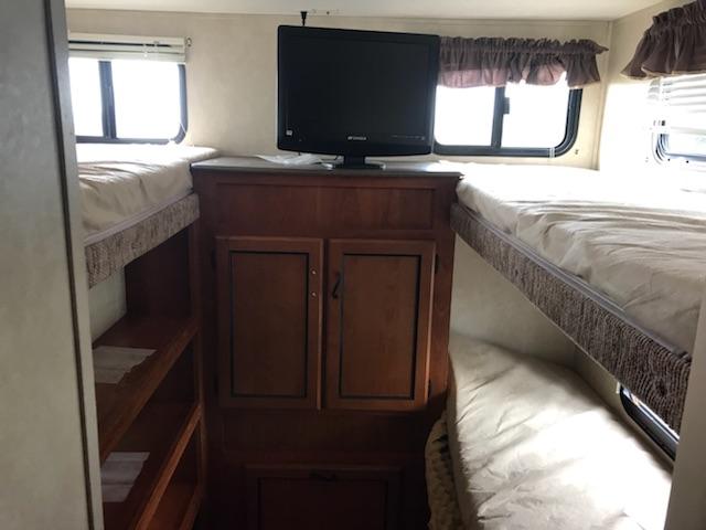 Cozy RV rental interior features four bunk beds, a central TV, and built-in storage for trips.. Coachman Freedom Express 2011
