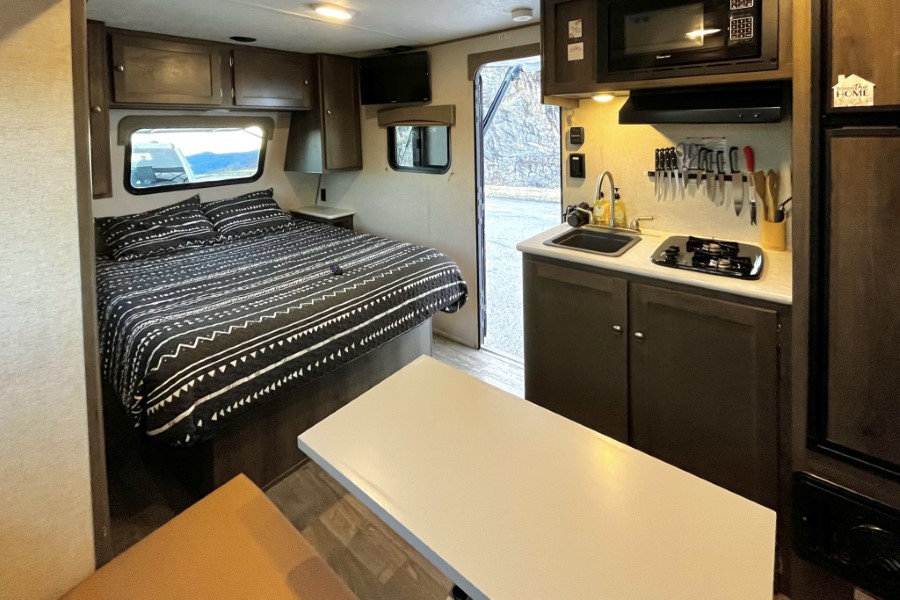 Spacious RV rental interior with a cozy bedroom, patterned bedding, and a well-equipped kitchenette & dinette.. Forest River Viking 2020