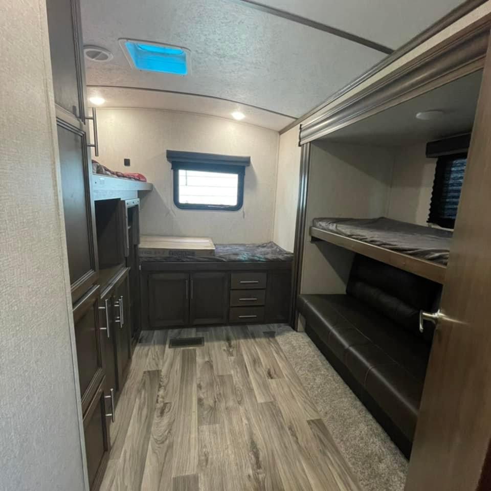 Spacious RV rental bunkhouse featuring multiple beds, storage, and a comfy sofa. Ideal for families and group travel.. Keystone RV Cougar 2020