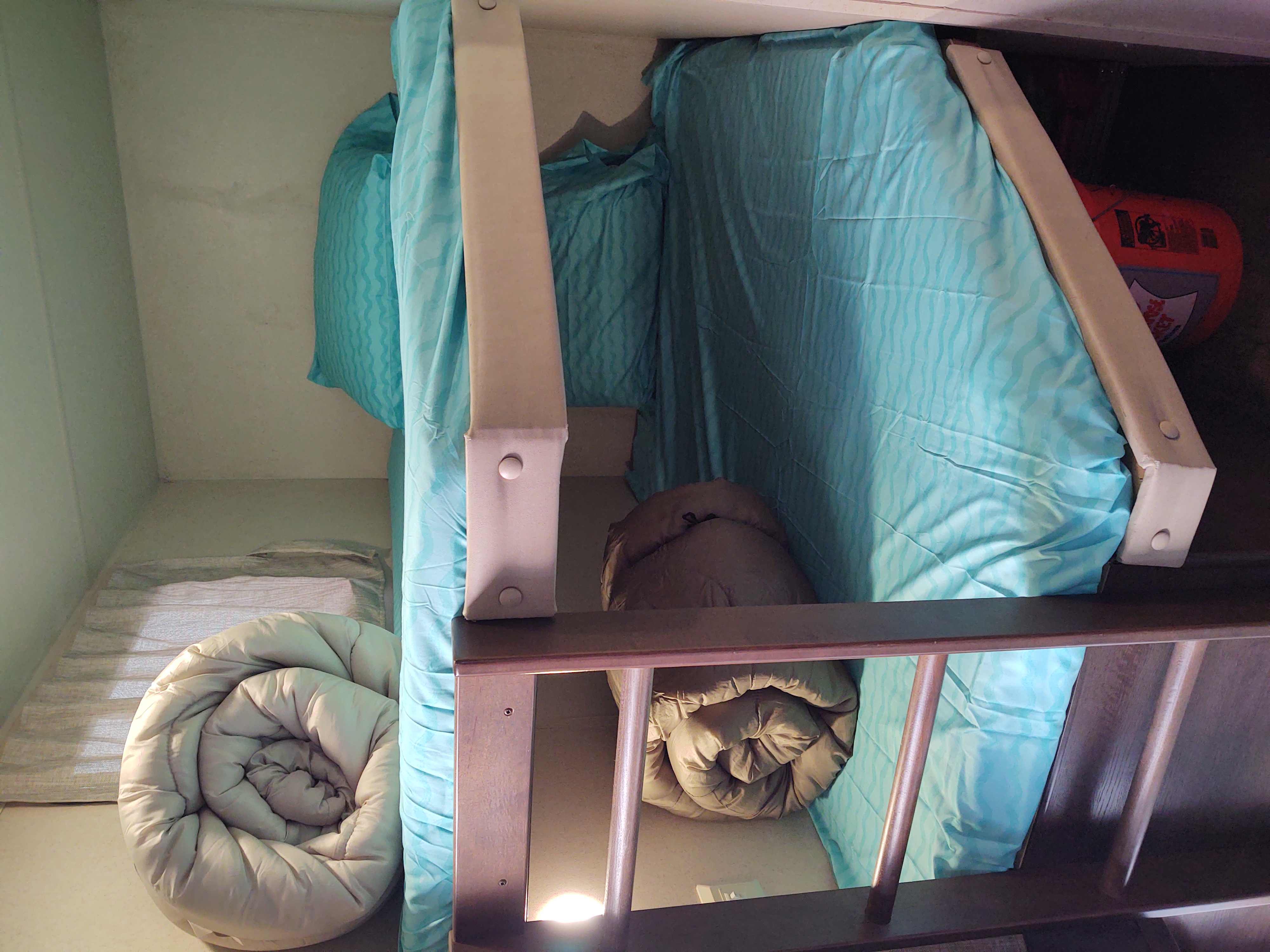 Cozy bunk beds in an RV rental. Top bunk has teal bedding, bottom has a rolled comforter. Compact sleeping space.. Forest River Salem 2019