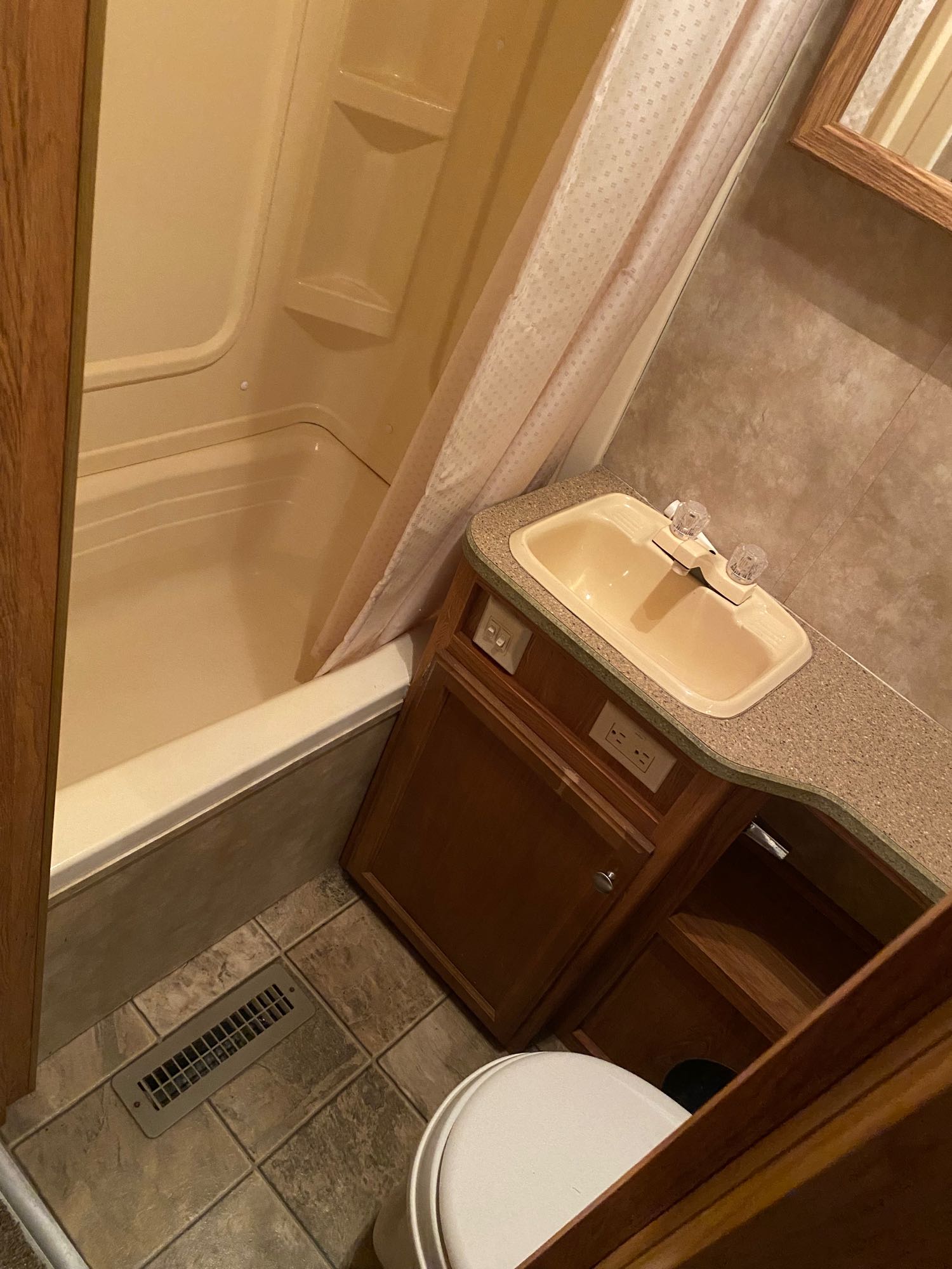 RV rental bathroom with a beige shower/tub, sink vanity, and partial toilet. Compact and functional for your travels.. Jayco Jay Feather 2007