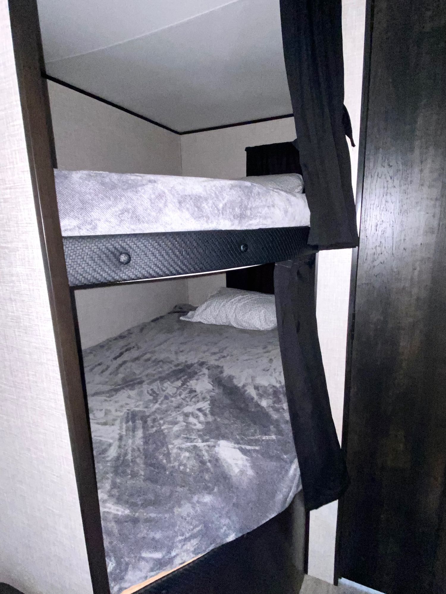 Compact RV rental interior featuring comfortable bunk beds with grey bedding and privacy curtains, ideal for family travel.. Jayco Jay Flight SLX 2022