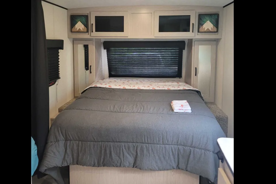 RV rental bedroom featuring a spacious bed, overhead storage, and window with blinds.. Coachman Apex Nano 208BHS 2022