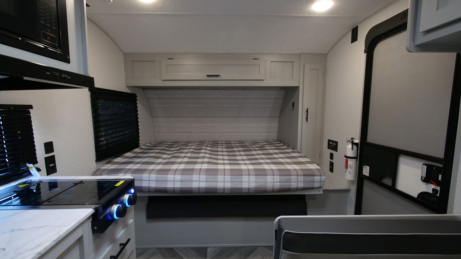 Inside a modern RV rental: a compact interior with a bed, overhead cabinets, and a small kitchen cooktop. Perfect for travel.. Forest River Salem FSX 2022