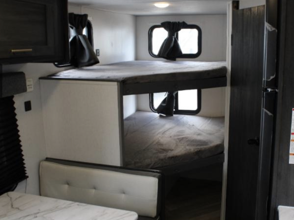 Compact RV rental interior featuring cozy bunk beds, a dinette, and storage. Ideal for travel trailer adventures.. Forest River Ozark 1650BHKX 2022