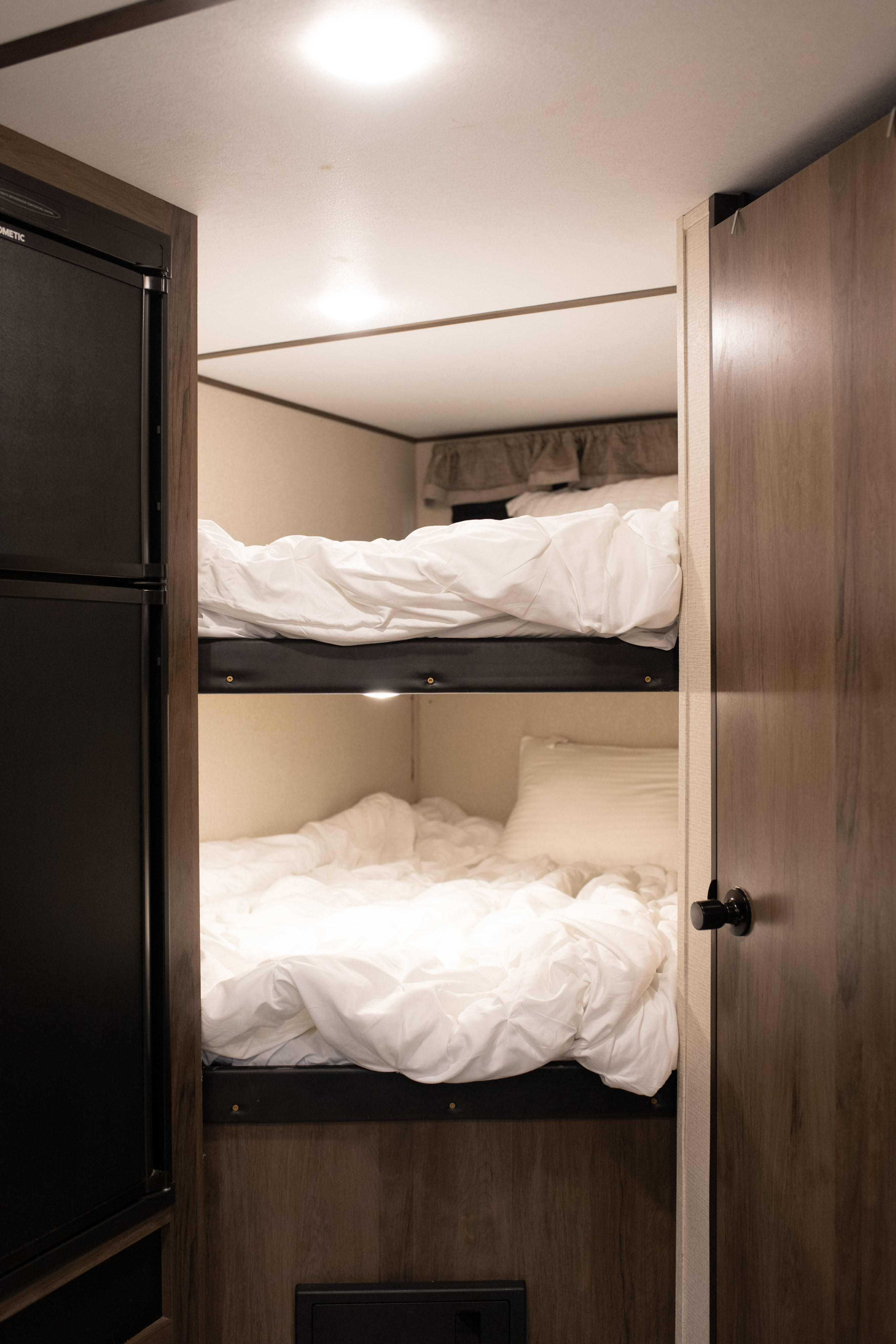Our RV rental features cozy bunk beds with white bedding, plus a fridge and storage, perfect for your adventure.. Avenger ATI 2020