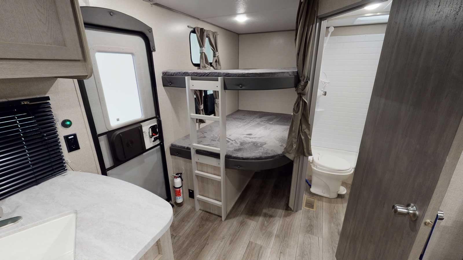 Spacious rv rental interior featuring bunk beds, a compact bathroom, and a functional kitchen area. Ideal for travel.. Forest River Catalina legacy 2023