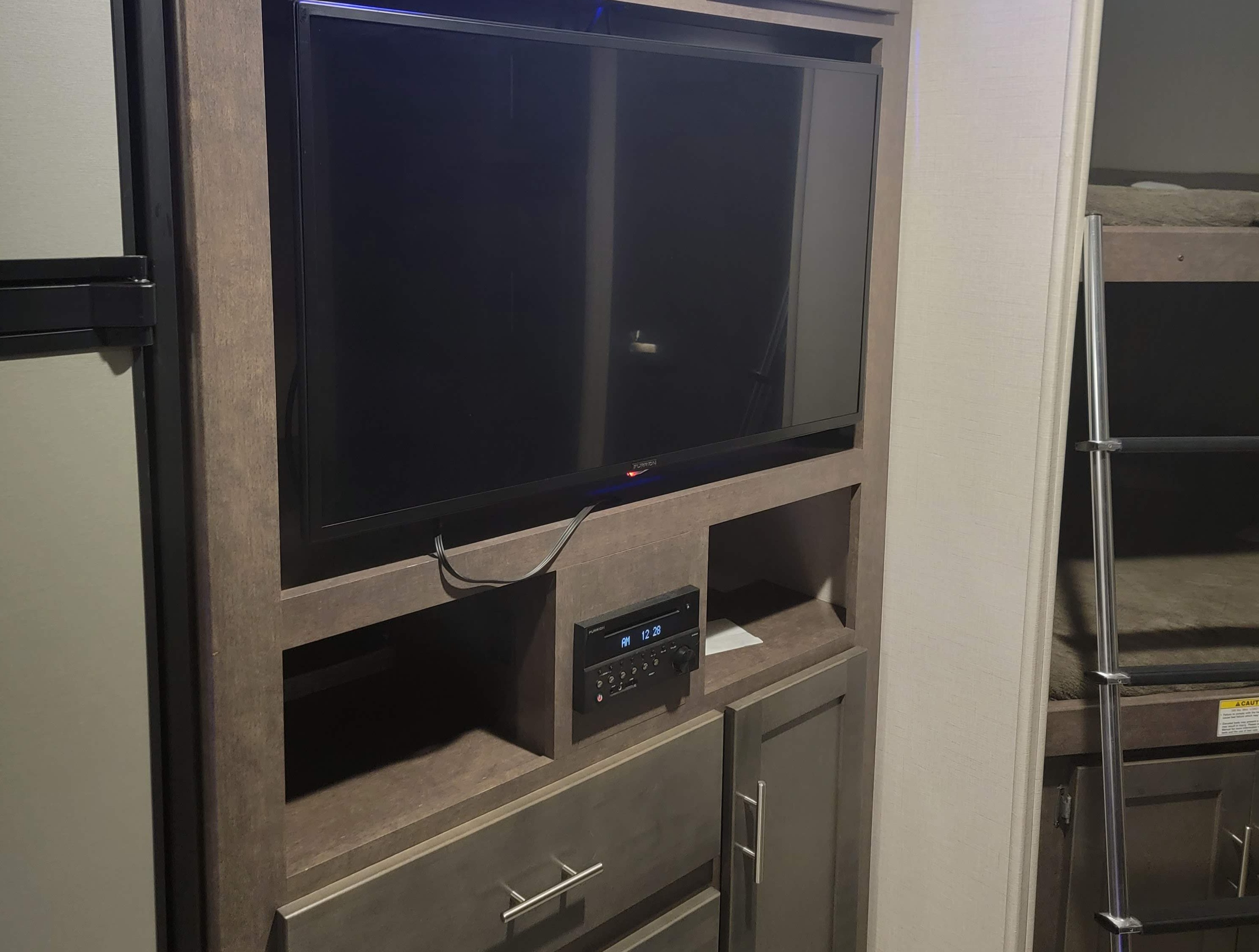 Inside an RV rental: Entertainment center with TV, stereo system, and adjacent bunk beds.. Crossroads RV Sunset Trail Super Lite 2019