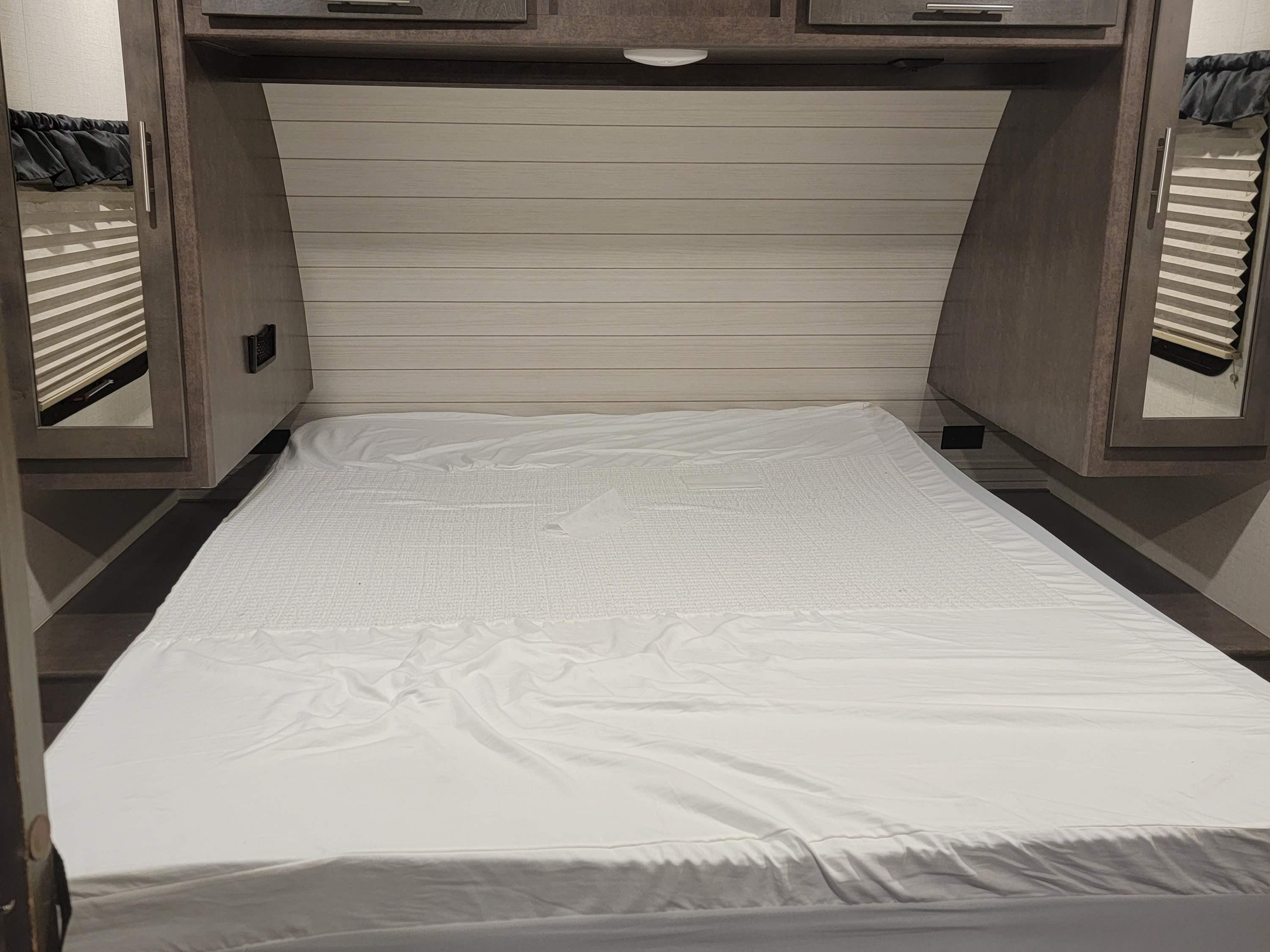 Clean RV rental bedroom with a neatly made bed, overhead cabinets, and window blinds, ready for a comfortable night's sleep.. Crossroads RV Sunset Trail Super Lite 2019