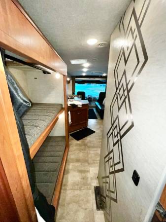 This RV rental features a narrow hallway, bunk beds on the left, and a decorative wall on the right leading to the main living area.. Winnebago Sunstar 2016