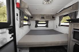 Step inside this RV rental! A compact camper interior with a large bed, overhead cabinets, and windows for your cozy travel adventures.. Prolite 12 V 2019