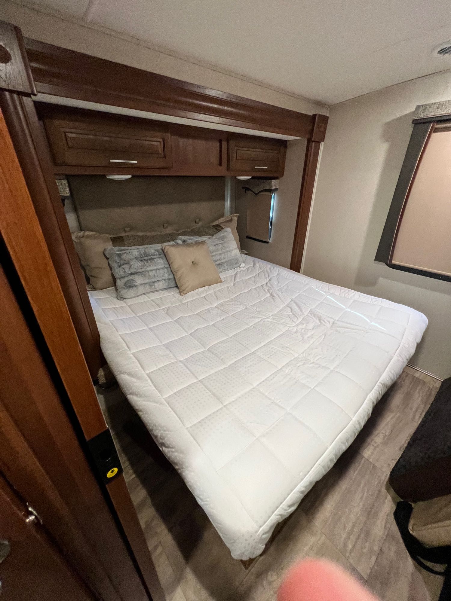 This RV rental bedroom features a comfy bed with a white quilted topper, dark wood cabinets, and a window.. Georgetown GT5 2018