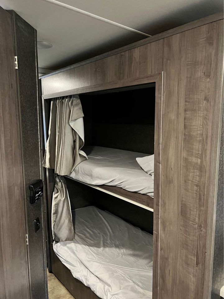 RV rental bunkhouse: two beds with light grey sheets and privacy curtains, ideal for extra sleepers.. Winnebago Minnie Winnie 2017