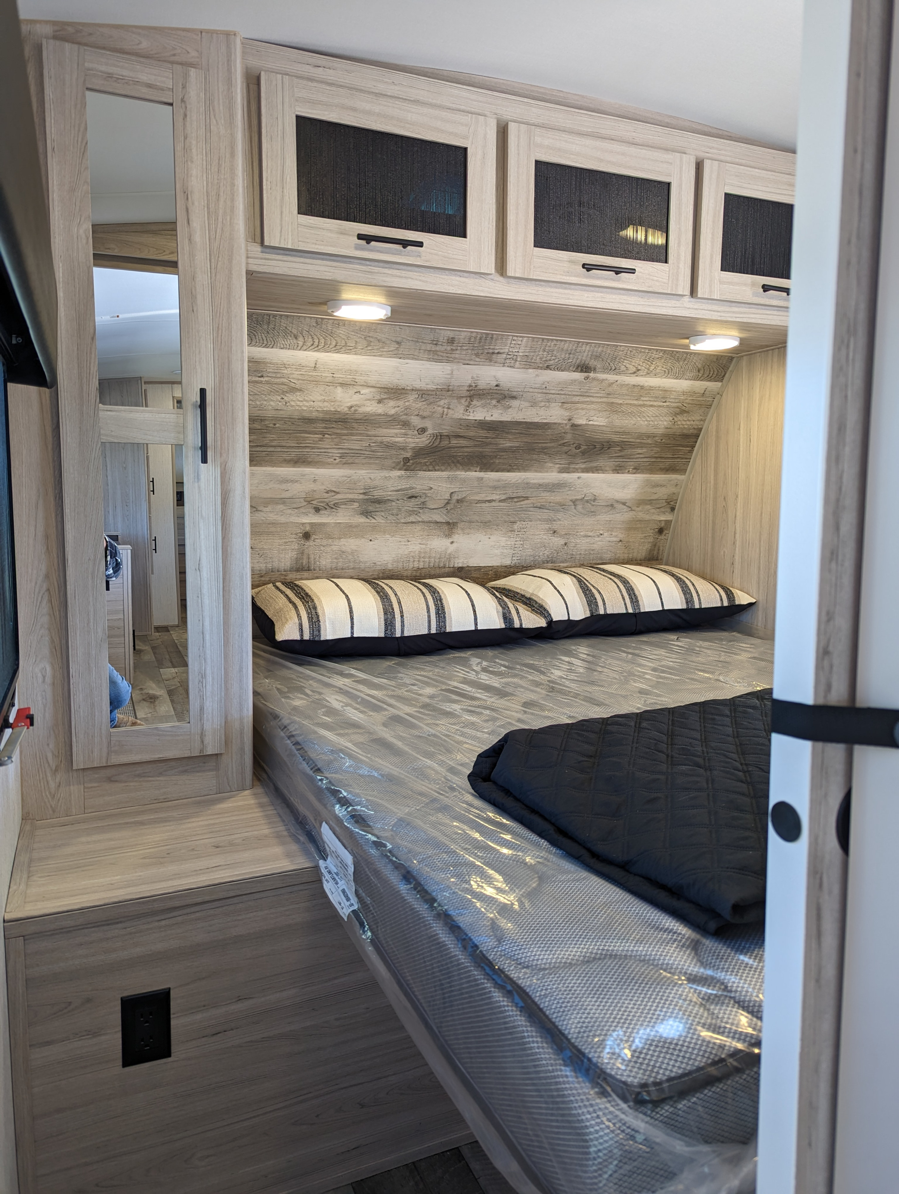 Modern RV rental bedroom with clean wood accents & new mattress, ready for travel.. Heartland Sundance 2022