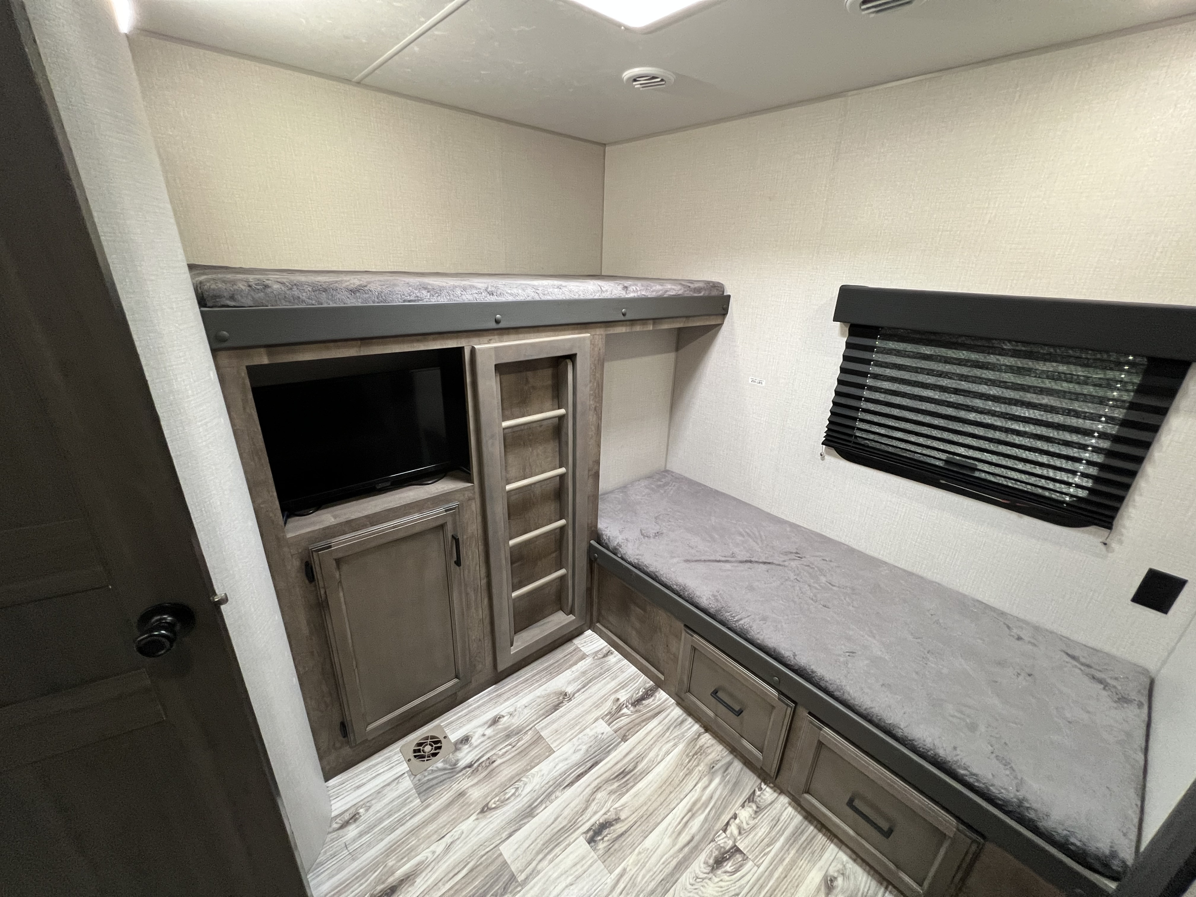 Compact **rv rental** bunk beds with a TV, storage drawers, and a window, offering a cozy sleeping area in a camper.. Sport Trek Sport Trek Trailer 2021