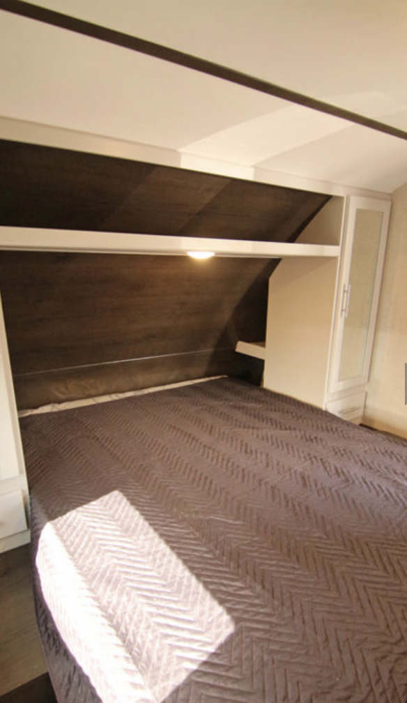 Compact RV rental bedroom with a comfy bed, integrated lighting, and smart storage for your travels.. Keystone RV Bullet Crossfire 2021