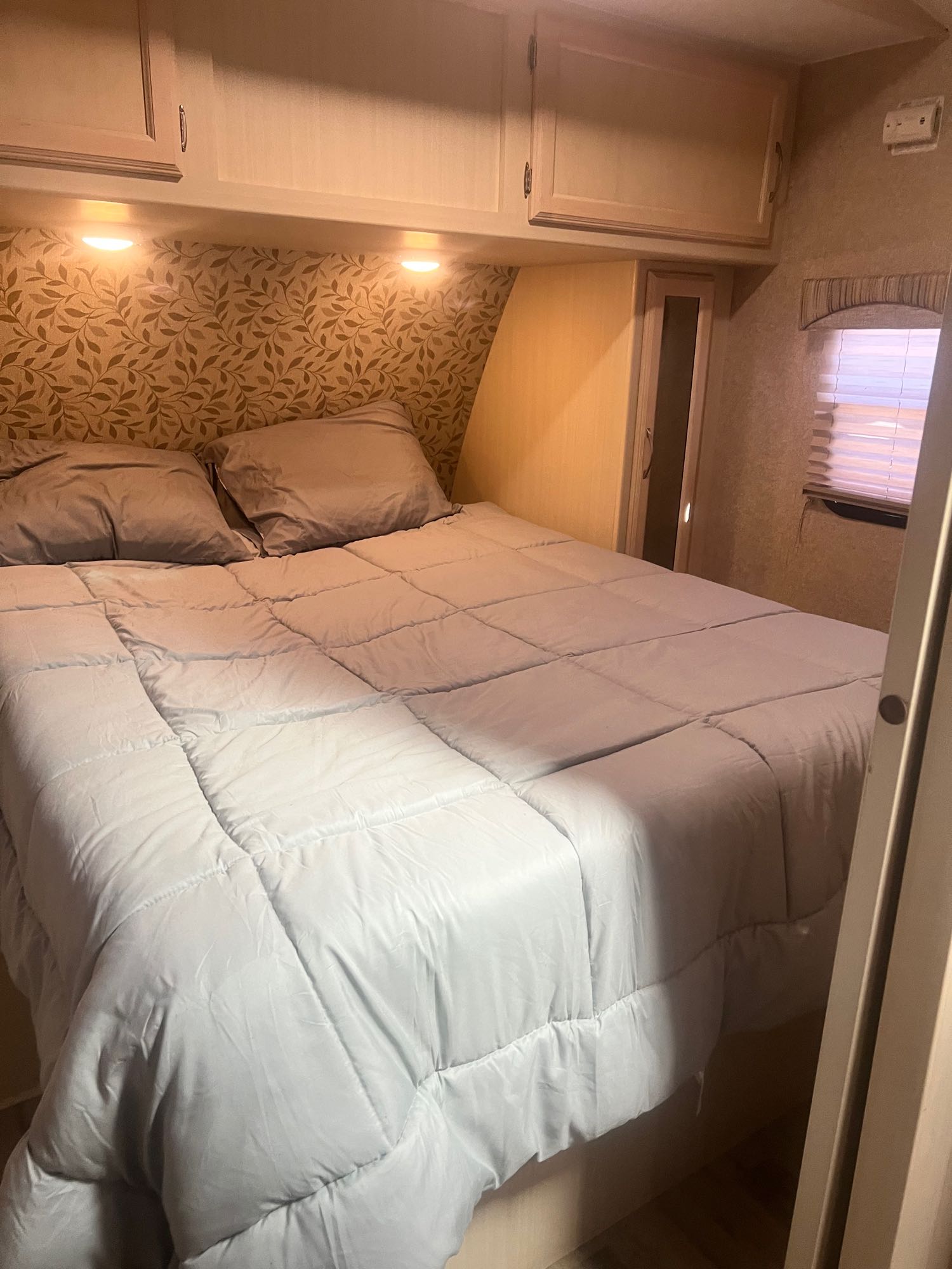Cozy RV bedroom with a comfy bed, overhead storage, and warm lighting, ideal for your next RV rental trip.. Minnie Minnie Plus 2017