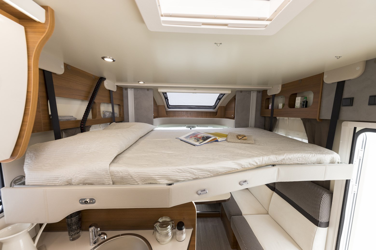 This RV rental interior features an elevated bed over a compact kitchen and seating, maximizing living space.. Elnagh Baron 565 2023