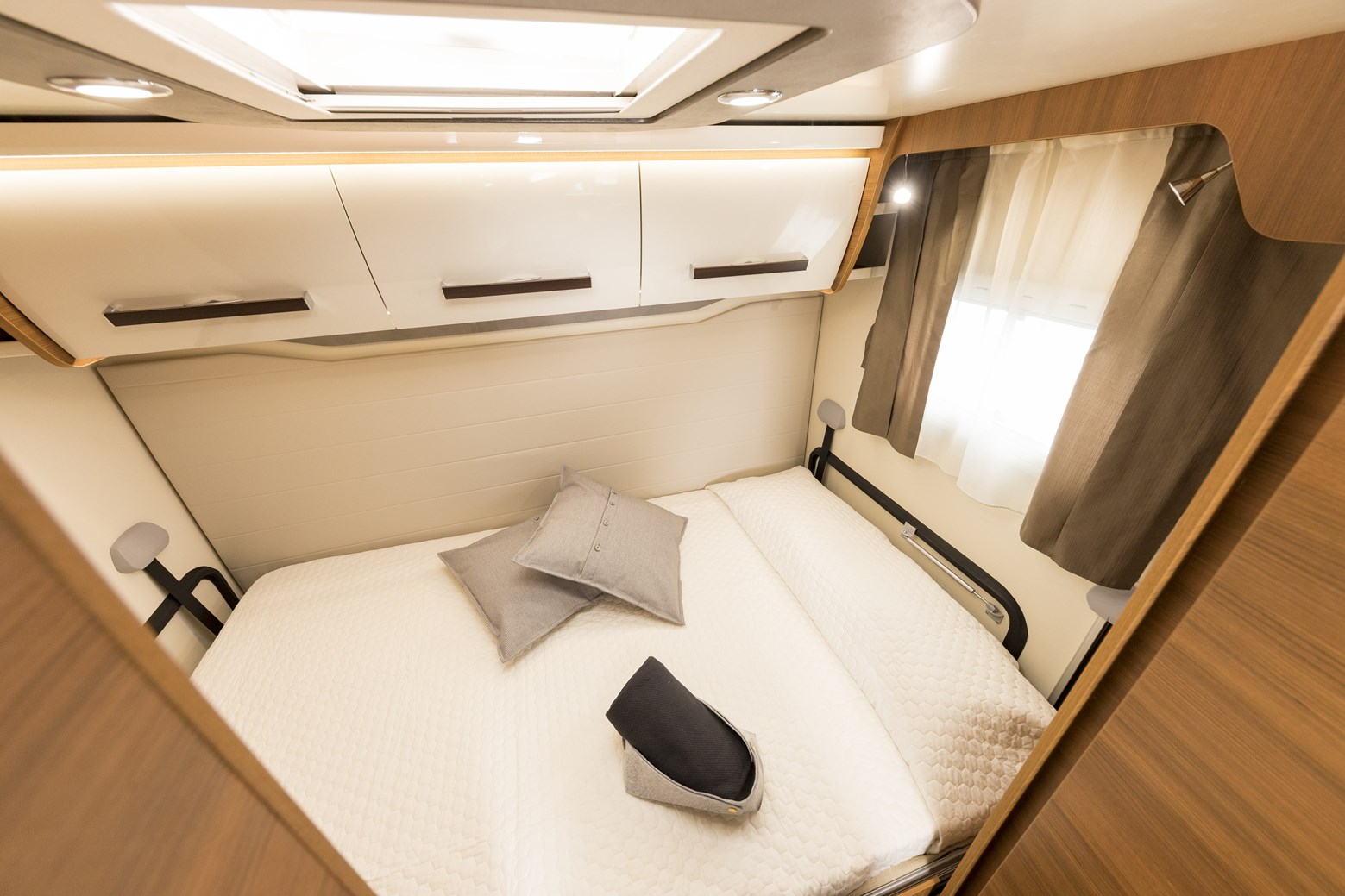 Discover the comfortable bedroom inside this RV rental, featuring a bed, overhead cabinets, and a window for natural light.. Elnagh Baron 565 2023