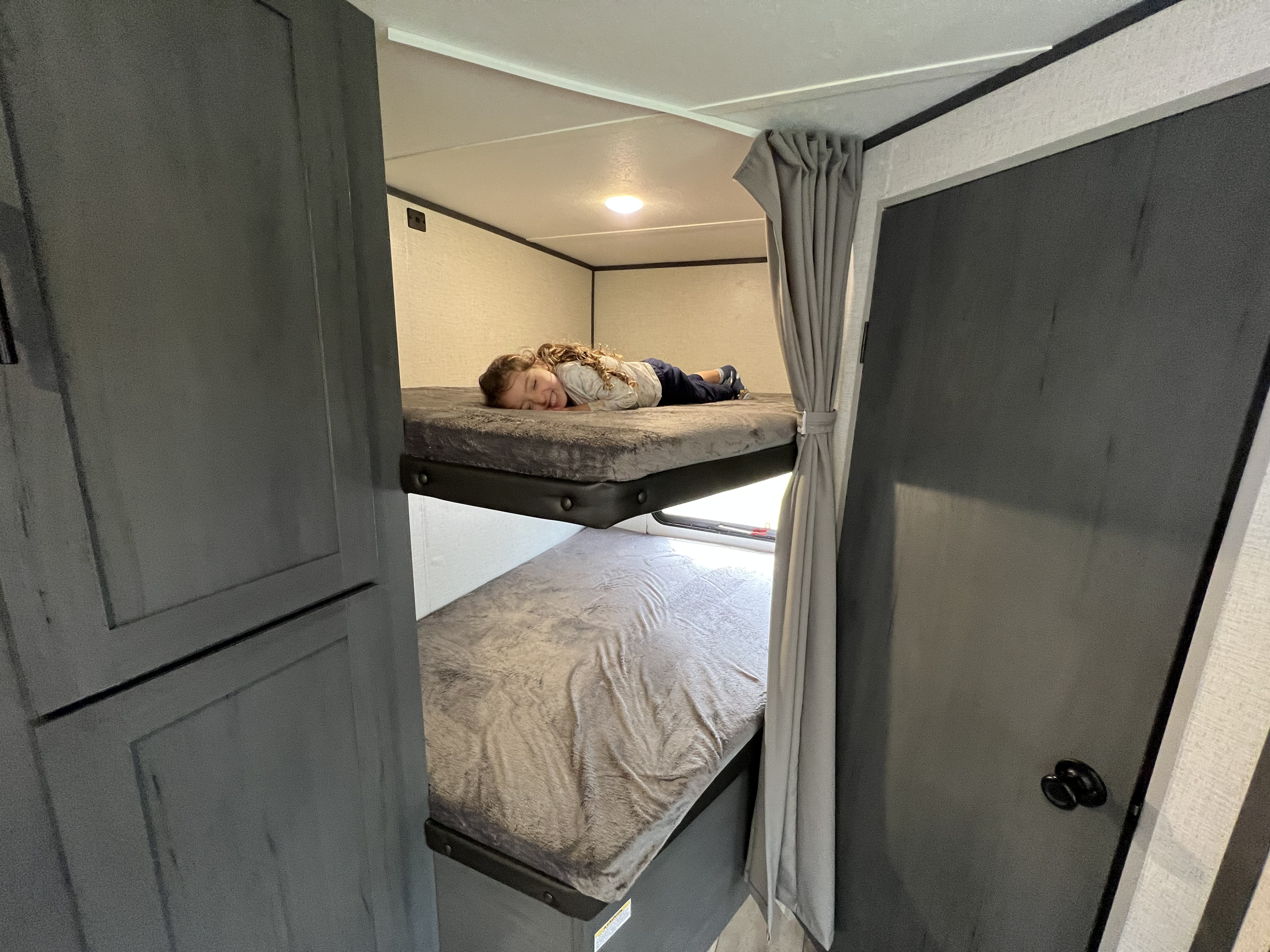 Happy child napping in cozy RV rental bunk beds, perfect for family adventures.. Aspen Trail LE 2022