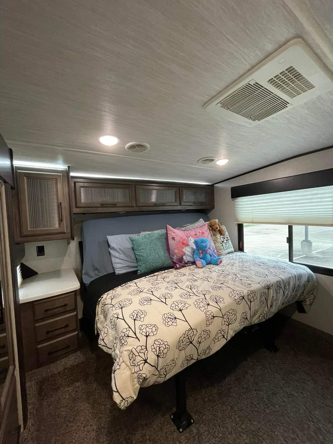 Cozy RV rental bedroom with a comfy bed, overhead cabinets, and AC unit, perfect for travel accommodations.. Heartland RVs Cyclone Toy Hauler 2019
