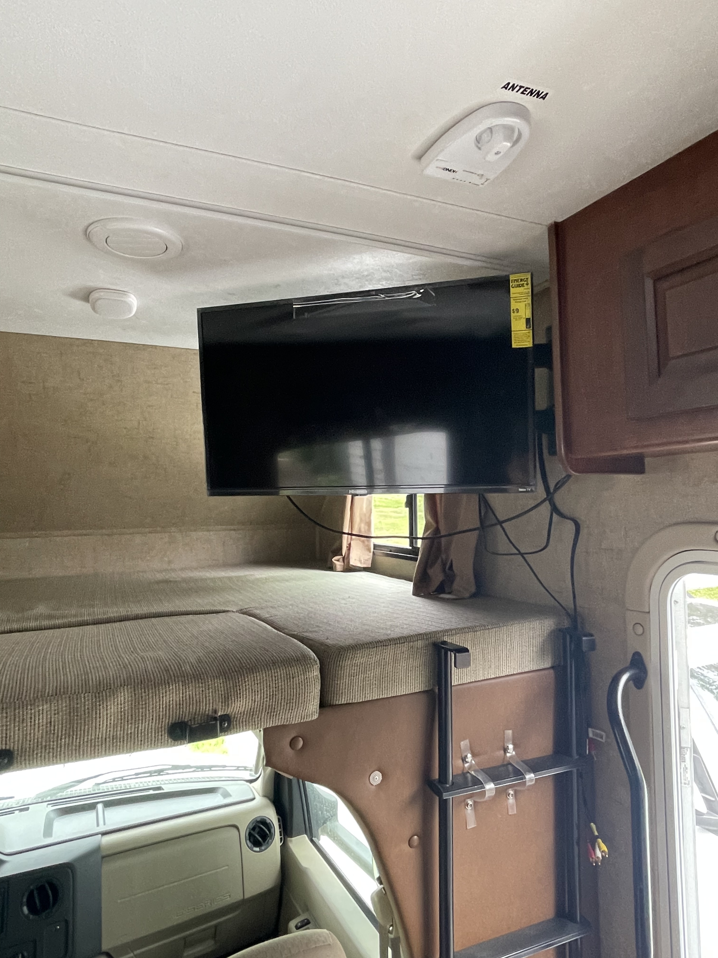 RV rental interior: bunk bed, mounted TV, antenna, and ladder, leading to the driver's area below.. Forest River Sunseeker 2016