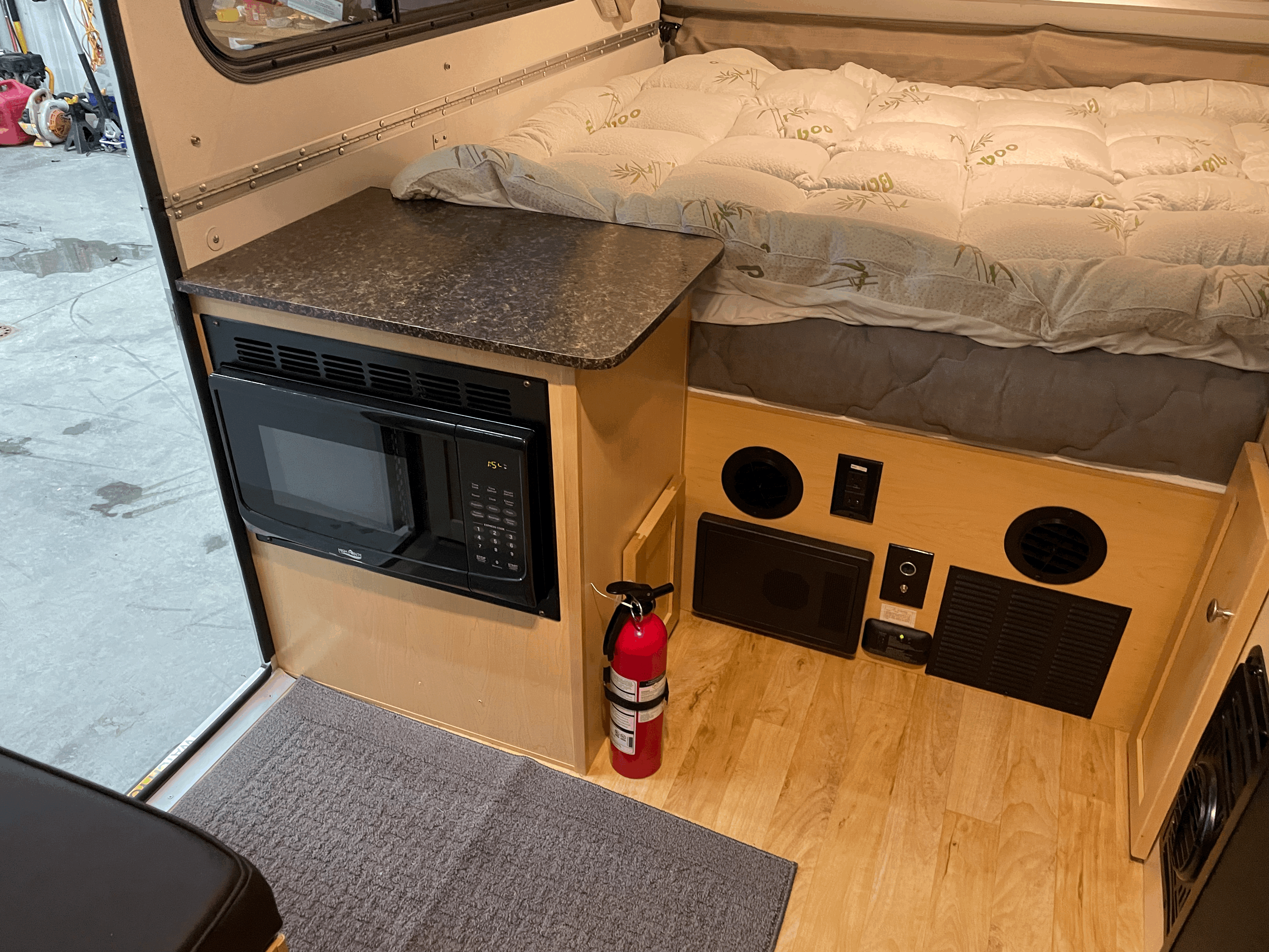 Cozy rv rental interior with bed, microwave, and essential safety gear like a fire extinguisher. Perfect for camping trips.. A Liner Other 2022