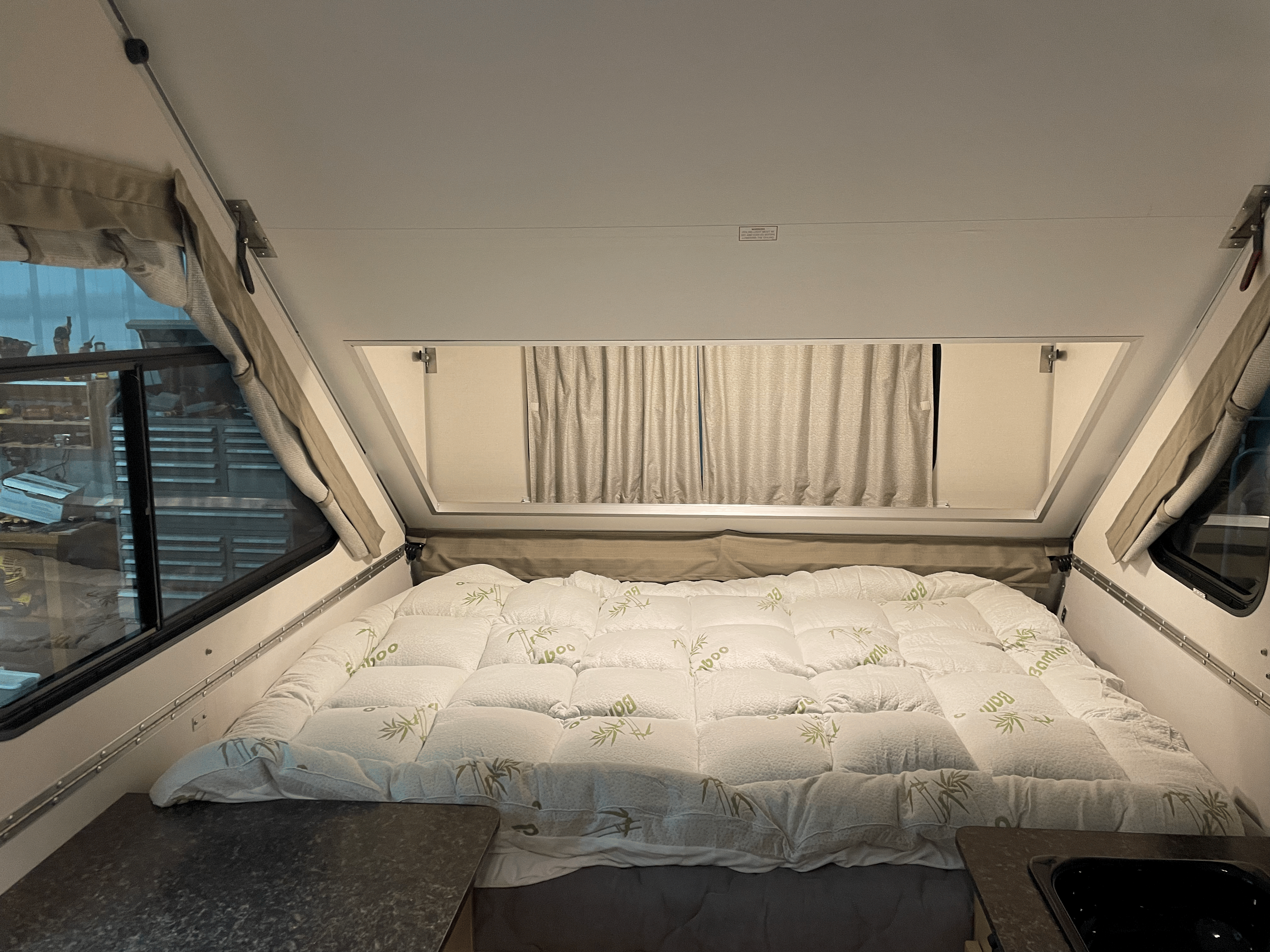 Explore this compact rv rental interior featuring a cozy bamboo-themed bed and side windows. Ideal for road trips!. A Liner Other 2022