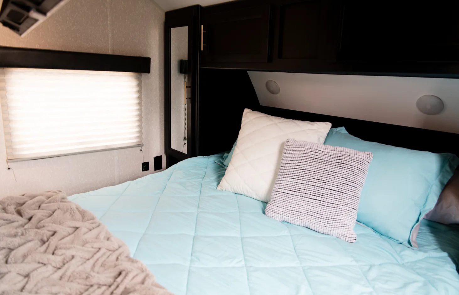 Queen-size bed in master with two sliding doors for privacy, closet storage on both sides of bed and above bed with a smart TV. Forest River Cherokee Grey Wolf 2022