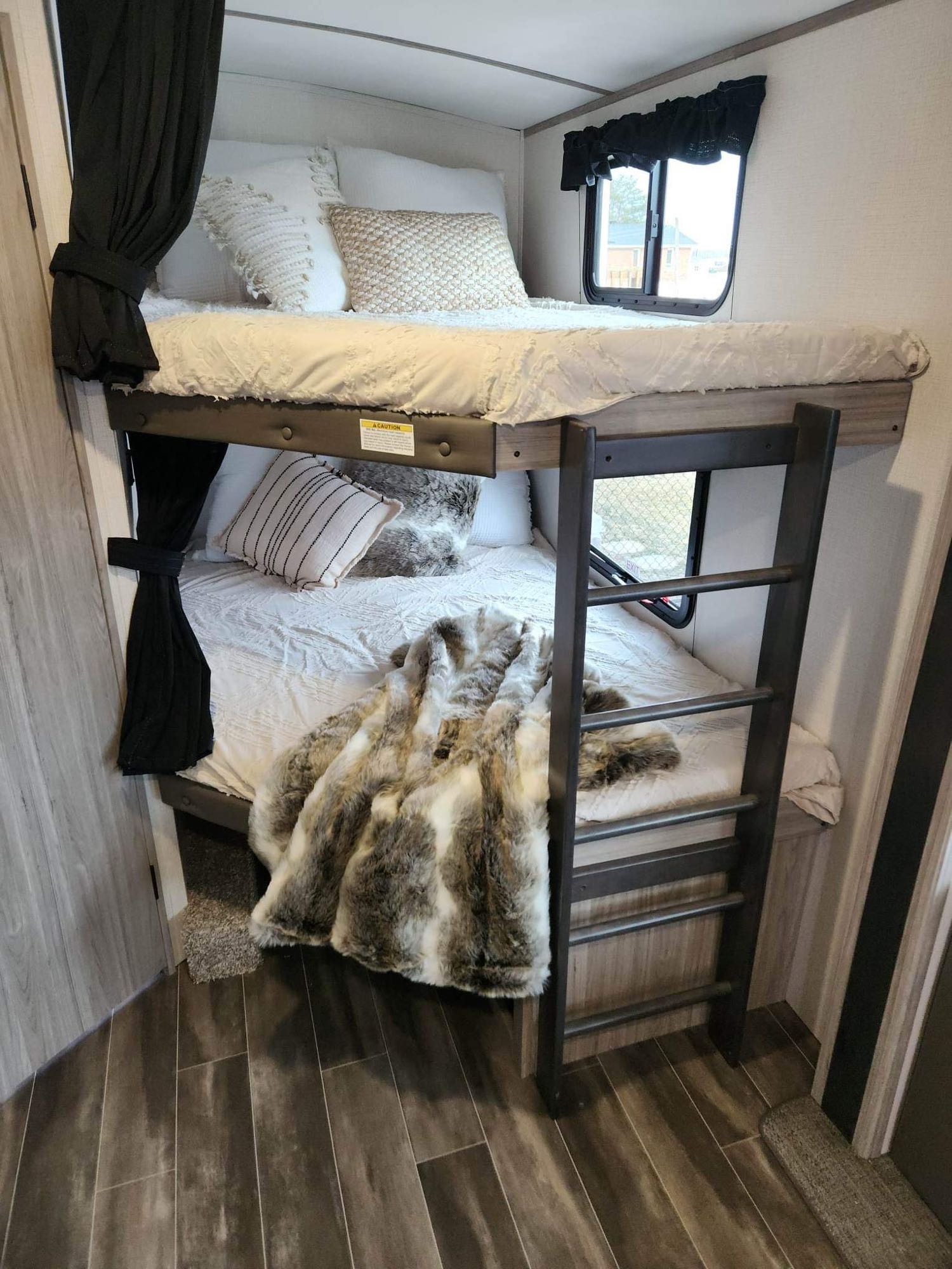 Cozy bunk beds with plush bedding and a ladder in an RV rental. Ideal for family travel, offering compact comfort.. Keystone RV Passport GT 2022