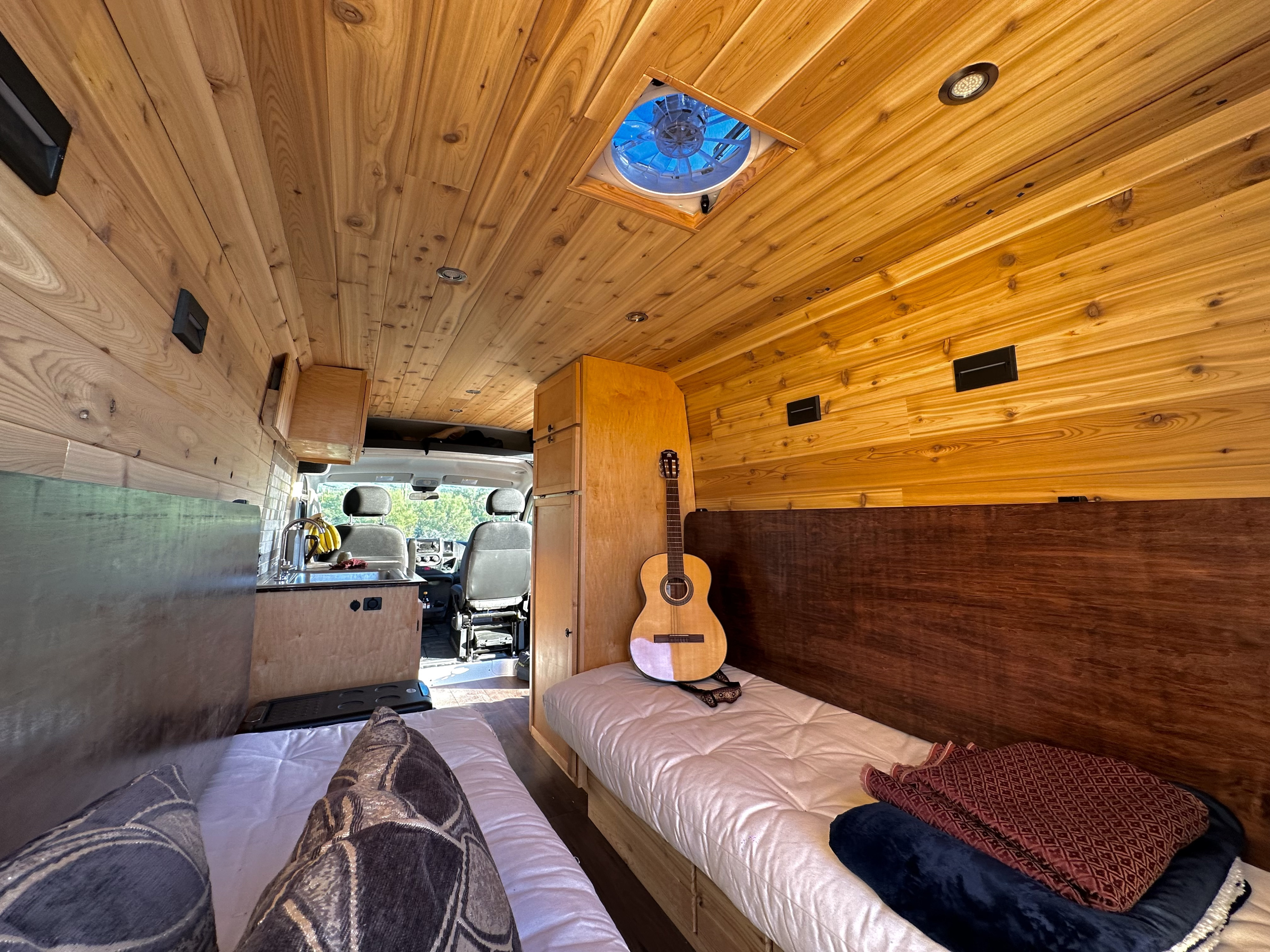 Spacious RV rental interior with custom wood finishes, dual beds, and a functional kitchen, perfect for mobile living.. Custom Promaster 2021 2021