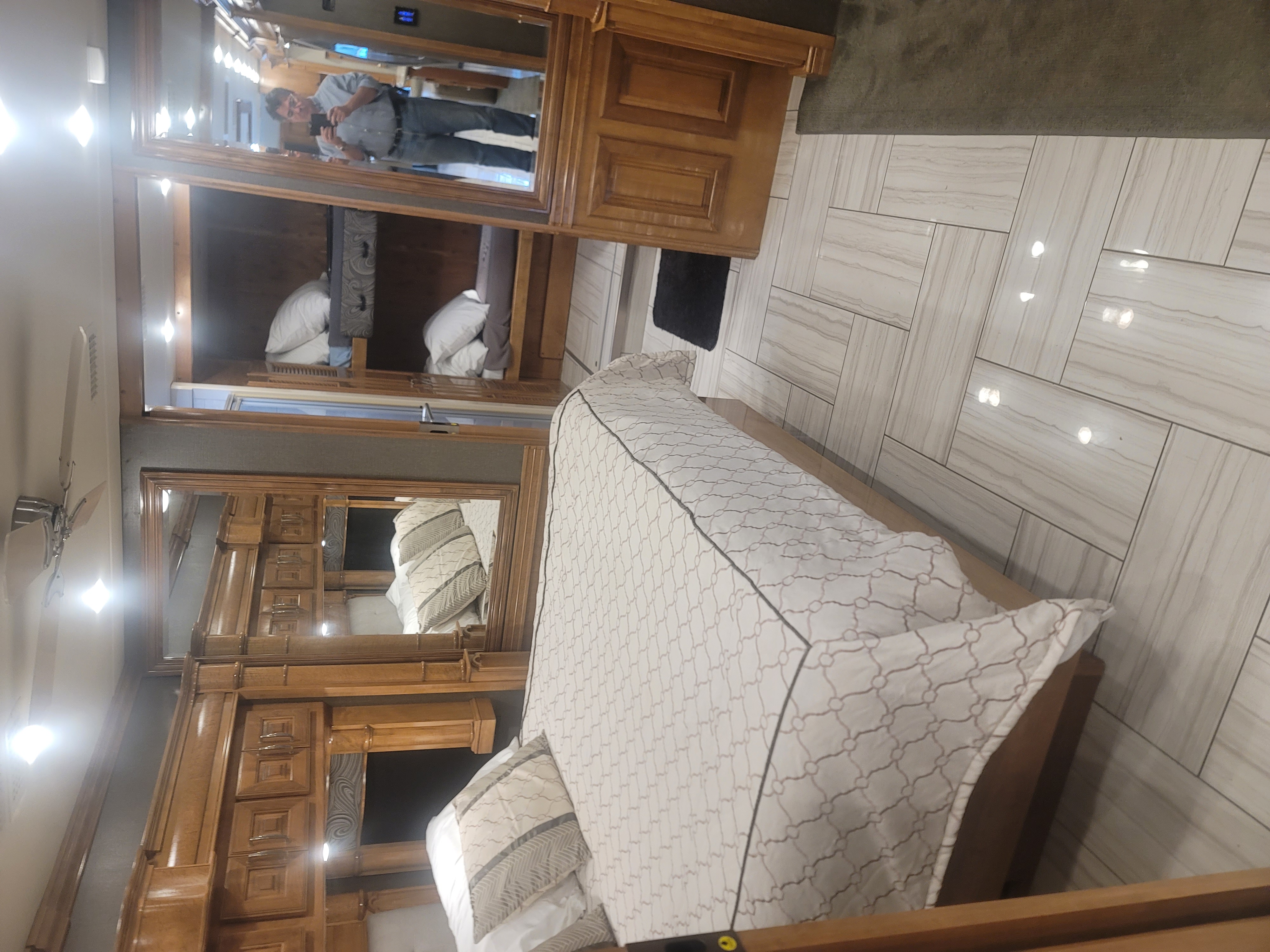 Spacious RV rental bedroom with a main bed, bunk beds, mirrored wardrobe, and bright, sleek tiled floor.. American Coach 42B 2019