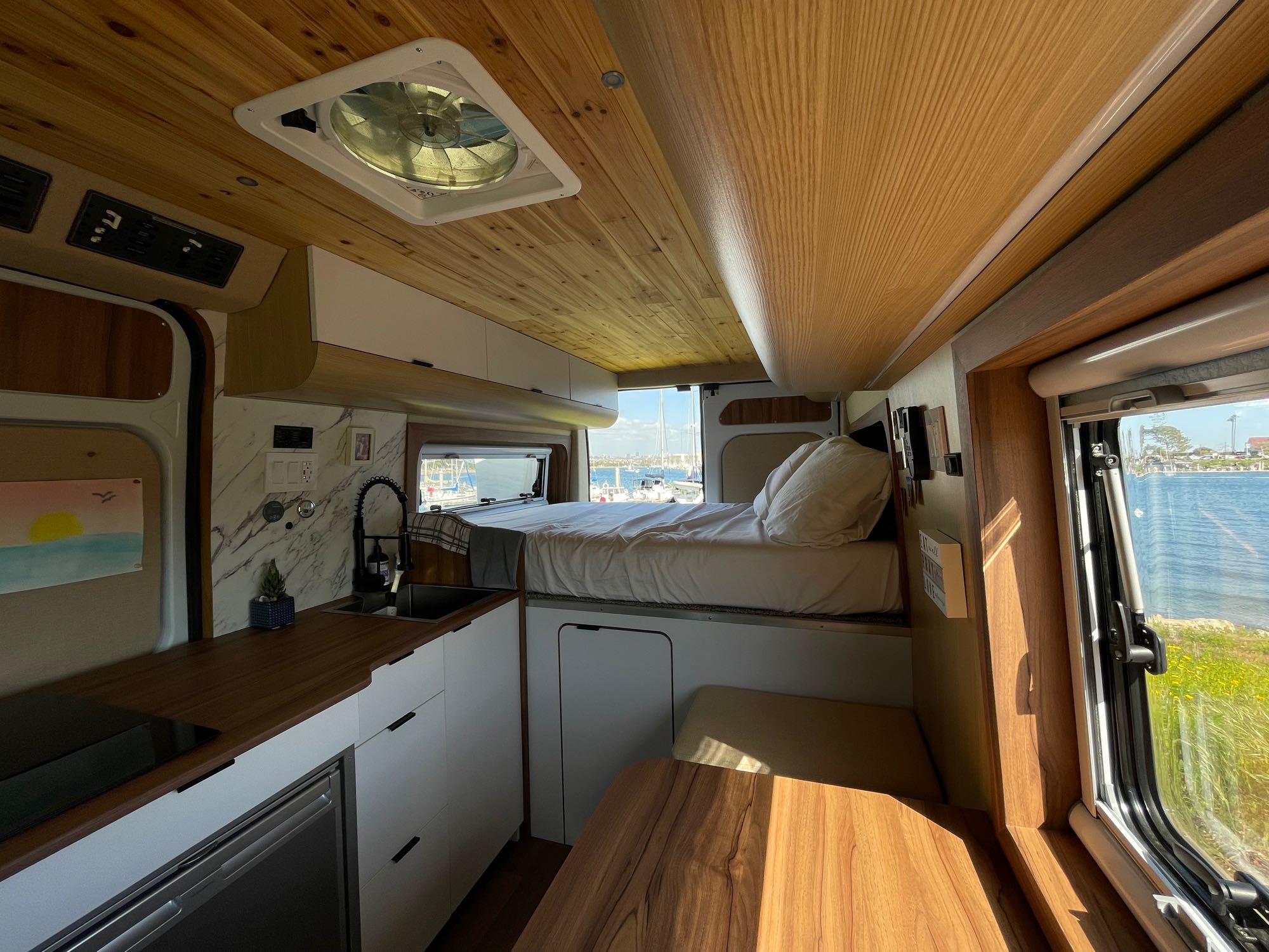 Discover this well-appointed rv rental camper van interior with a kitchen, raised bed, dining area, and waterfront views.. BEMYVAN B-Adventure 2022