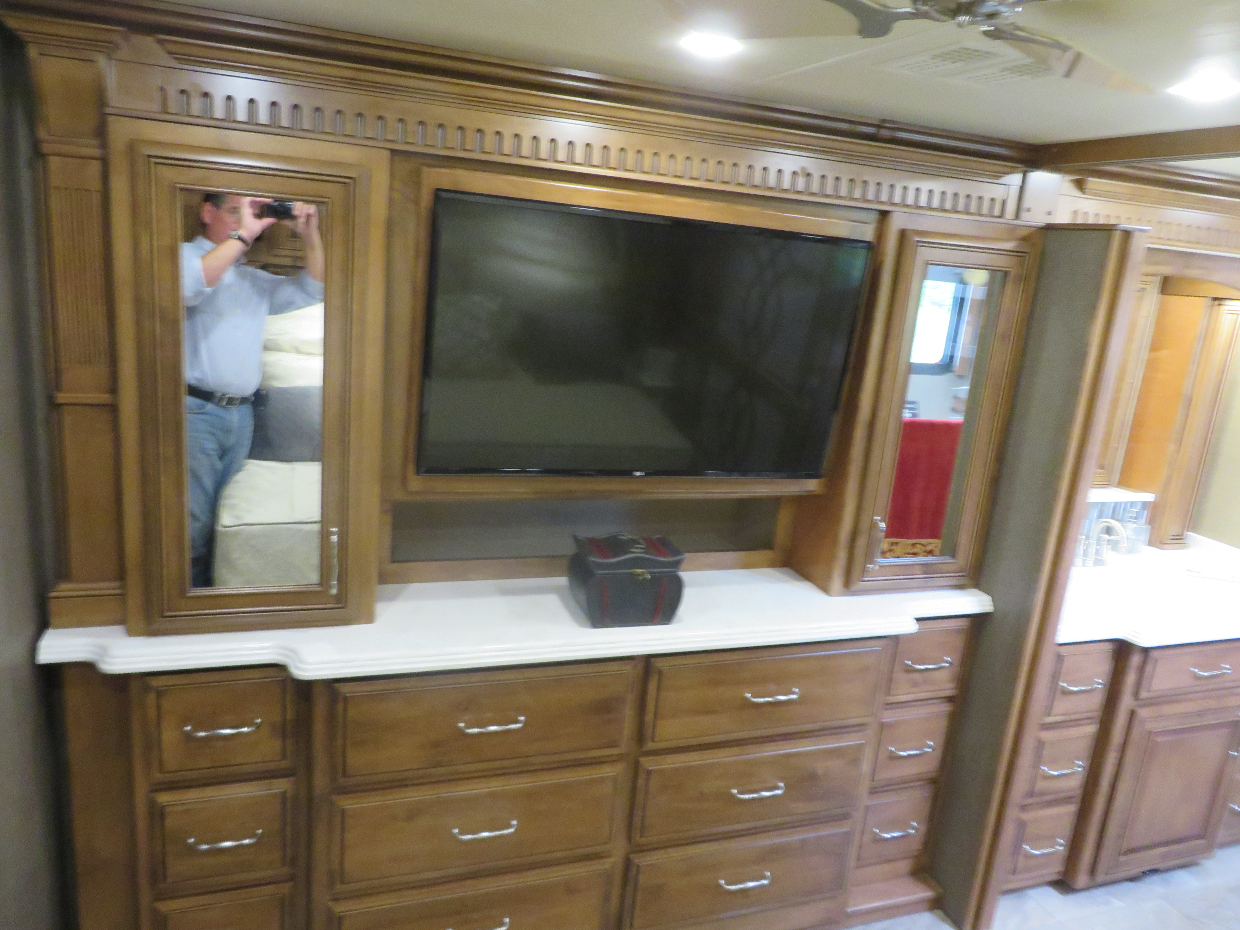 A roomy RV rental bedroom features a TV, mirror, and extensive wooden drawer storage.. Monaco Signature 2019