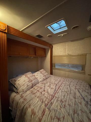 Cozy RV rental bedroom featuring a comfortable bed, overhead cabinetry, and a skylight on the ceiling.. Gulf Stream Conquest 2004