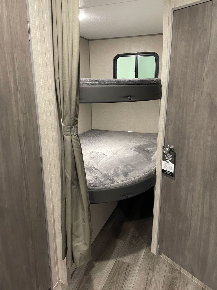 RV rental interior: cozy bunk beds with a window and privacy curtain. Ideal for family trips.. Coachmen Catalina 2023