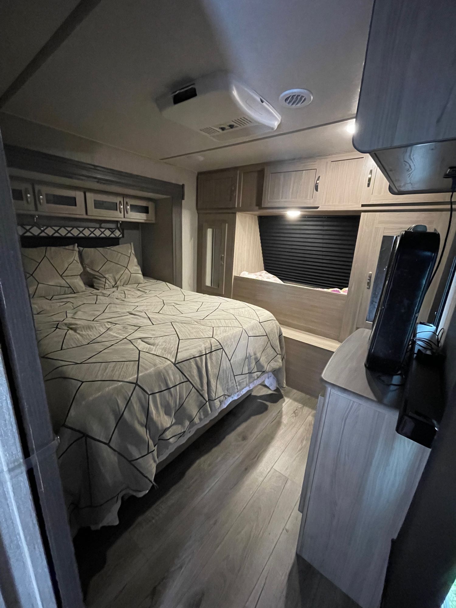 Modern RV rental bedroom: geometric bed, overhead cabinets, and wood-look floors. A comfortable, compact space for travel.. Coachmen Other 2021