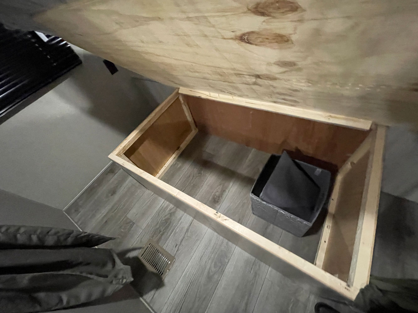 RV rental: Inside an RV's under-bed storage, showing wooden structure, grey floor, and a basket for gear.. Coachmen Catalina 2023
