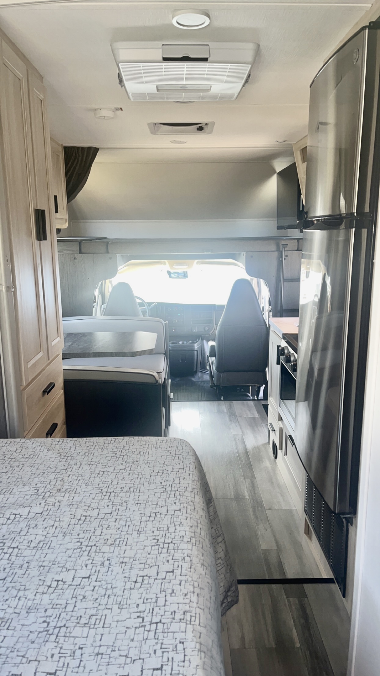 Inside a modern rv rental, observe the sleek kitchen with a large refrigerator, dinette, and front cockpit from the bed area.. Forest River Forester 2023