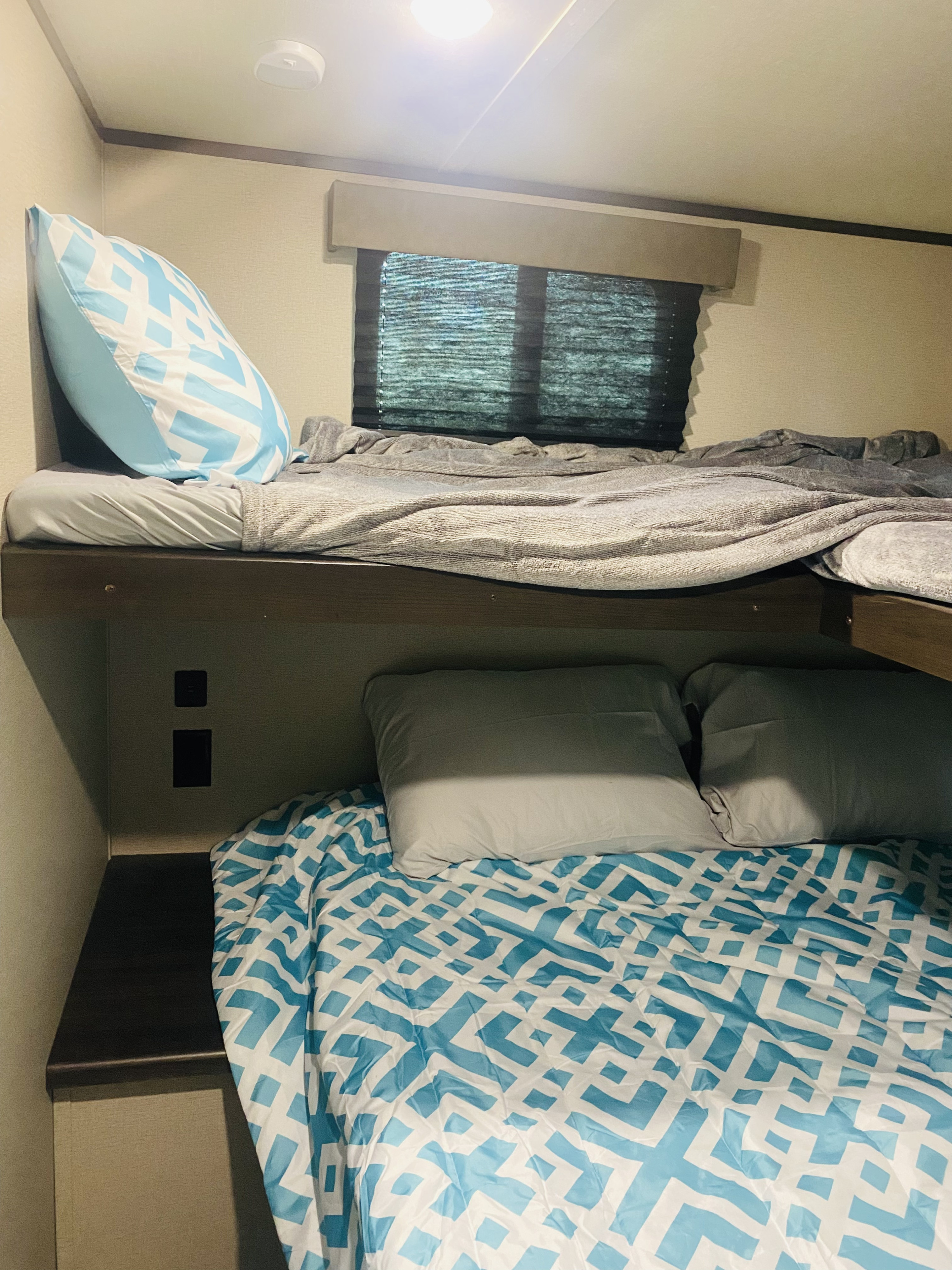Enjoy a comfortable RV rental with bunk beds. Features include a bright blue and white duvet & pillows, plus outlets on the bottom bunk.. Grand Design Transcend Xplor 2021