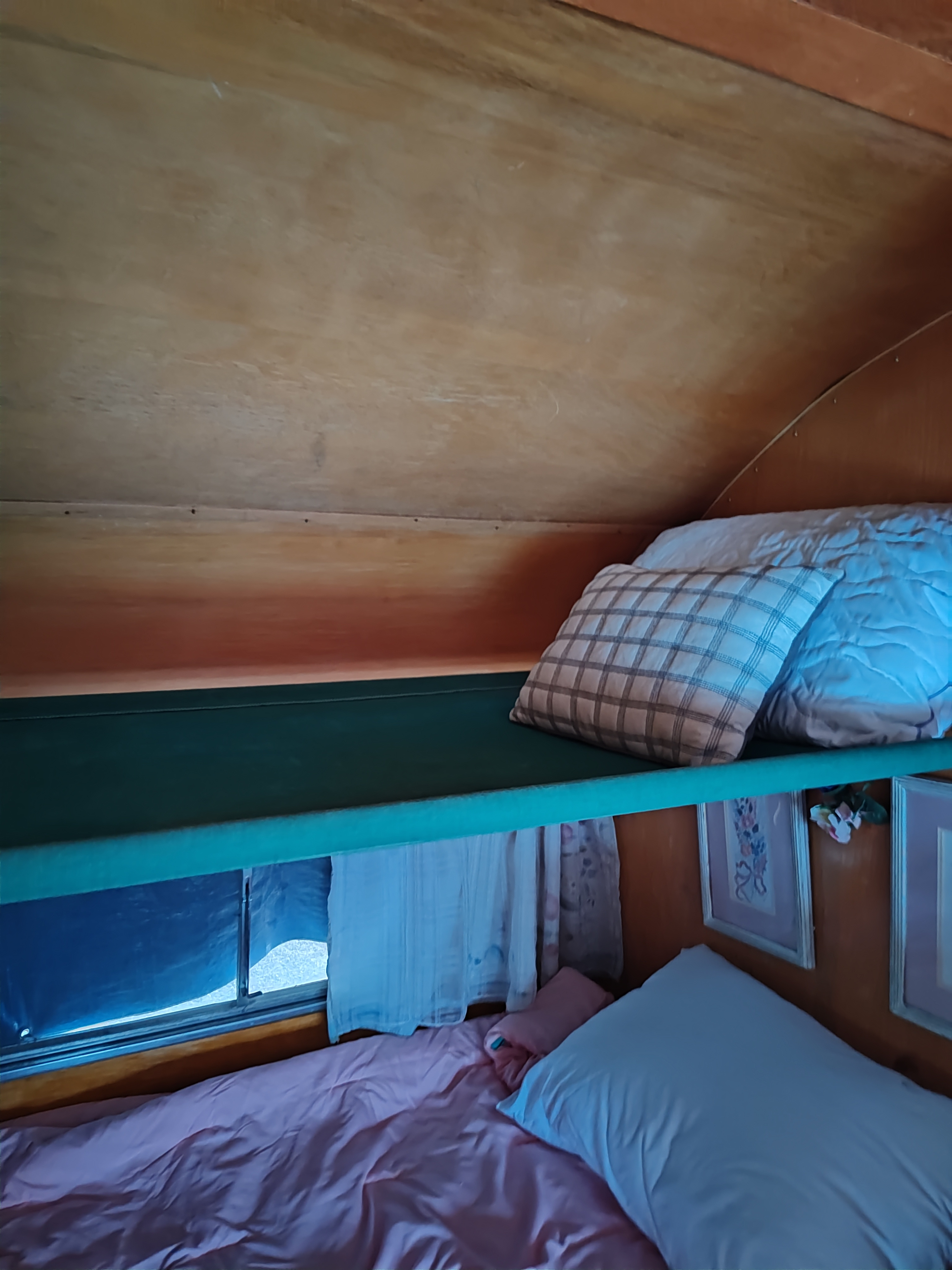 Cozy RV rental interior with comfortable bunk beds, ideal for a relaxing stay. Shows a bunk and lower bed.. Nomad camp trailer 1957