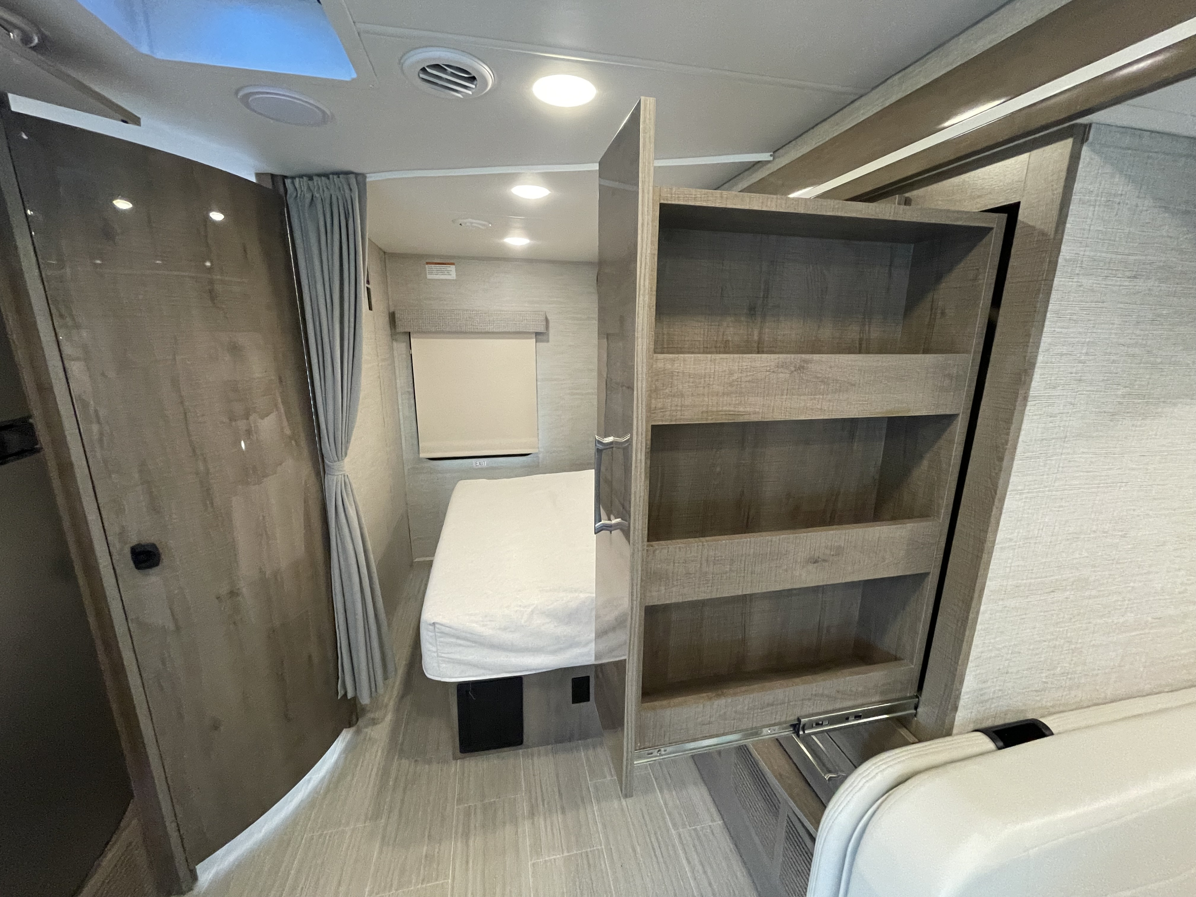 Inside an RV rental: a compact bedroom with an emergency exit window and a pull-out pantry offering smart storage space.. Jayco Melbourne 2022
