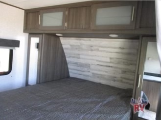 Experience comfort in this RV rental bedroom featuring a large bed, stylish wood-paneled headboard, and ample overhead storage.. Dutchmen Kodiak Ultra Lite 2020