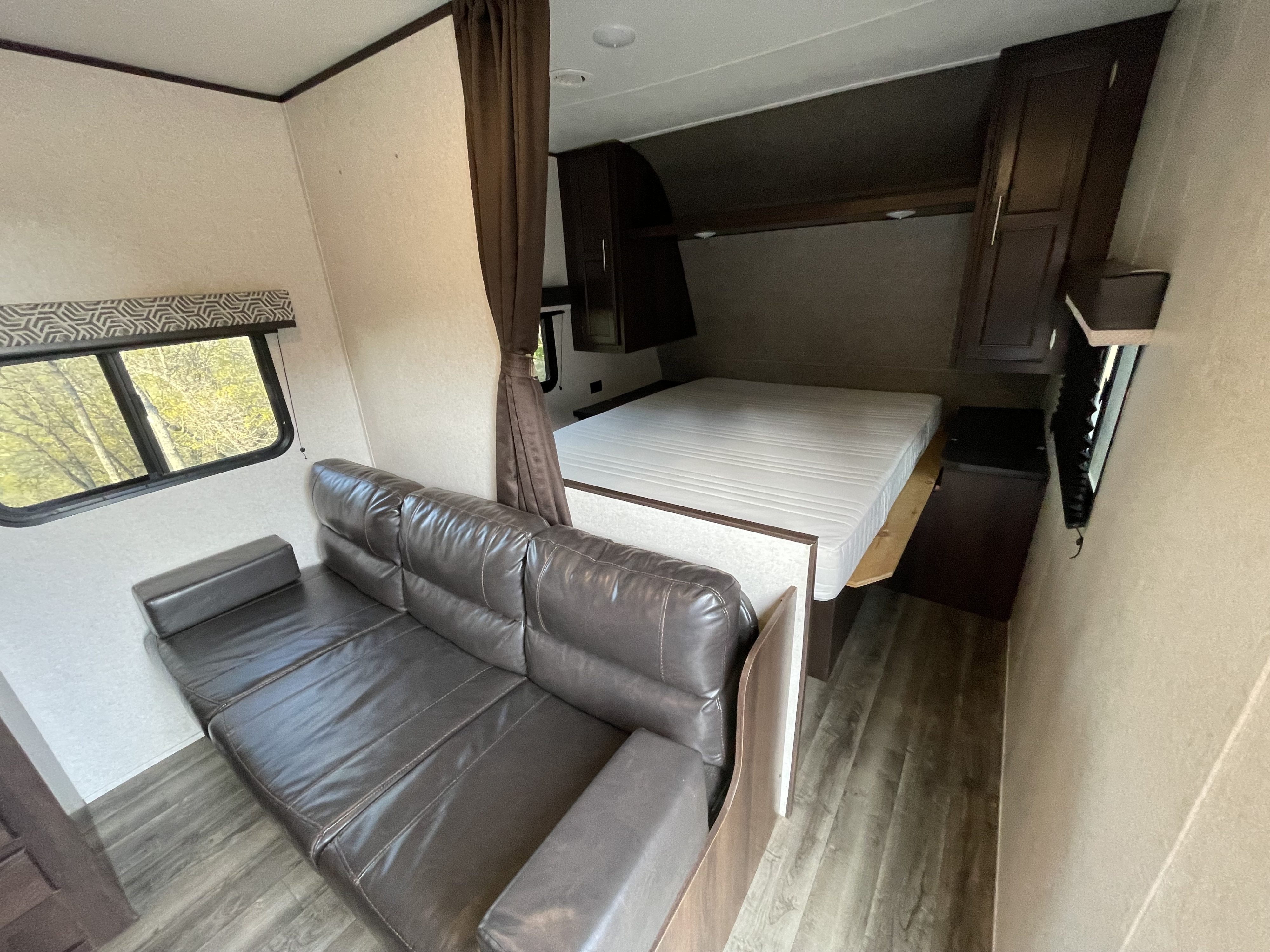 Inside this RV rental: a comfy brown sofa in the living space, leading to a queen bed and overhead cabinets.. Jayco Jay Flight SLX Baja Edition 2019